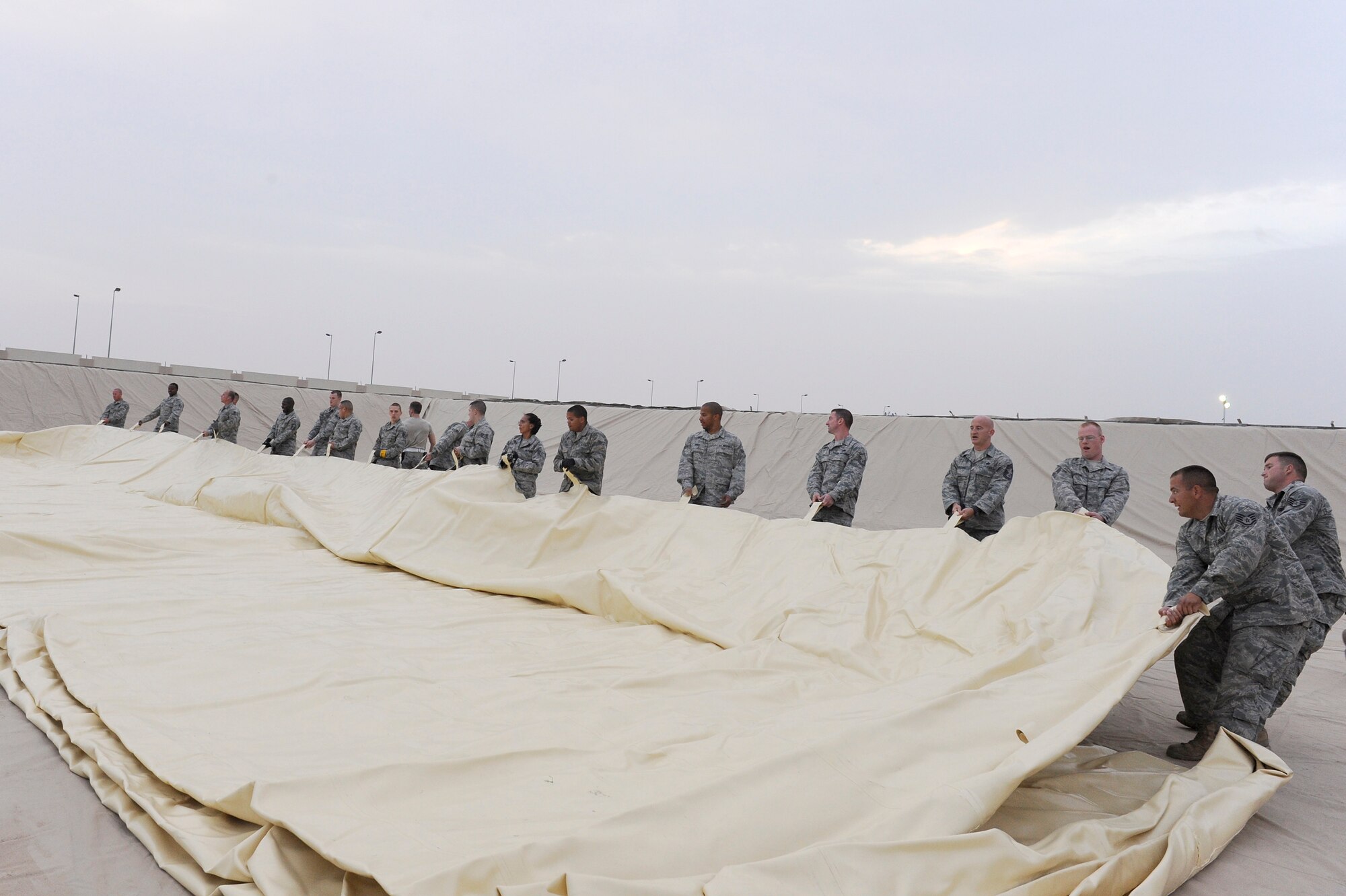 Members of the 380th Expeditionary Logistics Readiness Squadron, fuels flight roll out a fuel bladder, April 3 at an undisclosed location in Southwest Asia. The fuel bladder weighs about 6,000 pounds when empty. The new bladder will be filled with over 200,000 gallons of fuel. (U.S. Air Force photo by Senior Airman Brian J. Ellis) (Released)