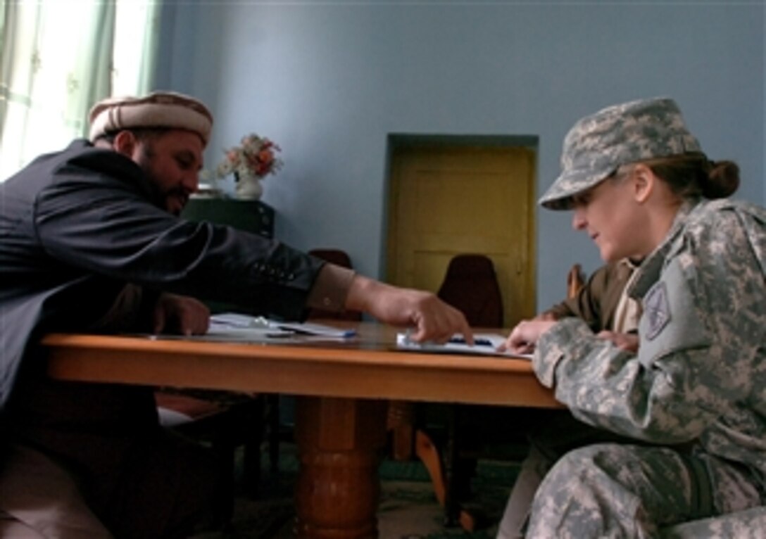 U.S. Army Maj. Kimberly Riggs, an engineering officer in charge of the Paktya Provincial Reconstruction Team, reviews a contract proposal with a local elder following a bidder's conference at the Governor's compound in Gardez in the Paktya province of eastern Afghanistan on April 2, 2009.  