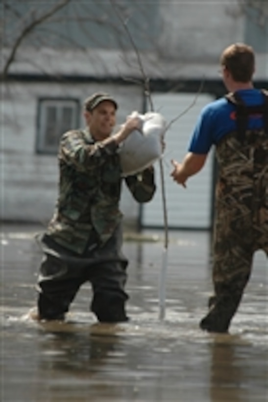 U.S. Air Force Master Sgt. Eric Johnson, 119th Wing, North Dakota Air National Guard, passes a sandbag along a human chain of flood fighters standing in knee-high floodwater southeast of Kindred, N.D., on April 21, 2009.  Johnson is helping the group build a temporary flood levee to hold back rising water near a farmhouse.  High water from the Sheyenne River is making its way over land and across roads posing a threat to residents of Cass County, N.D.  