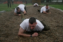 Marine Officer Candidates low crawl their way to the end of an obstacle course during Officer Candidate School Preparation weekend at Camp Dodge, Des Moines, Iowa,  April 25. The OCS Prep weekend is designed to give candidates a glimpse into what OCS life is like.