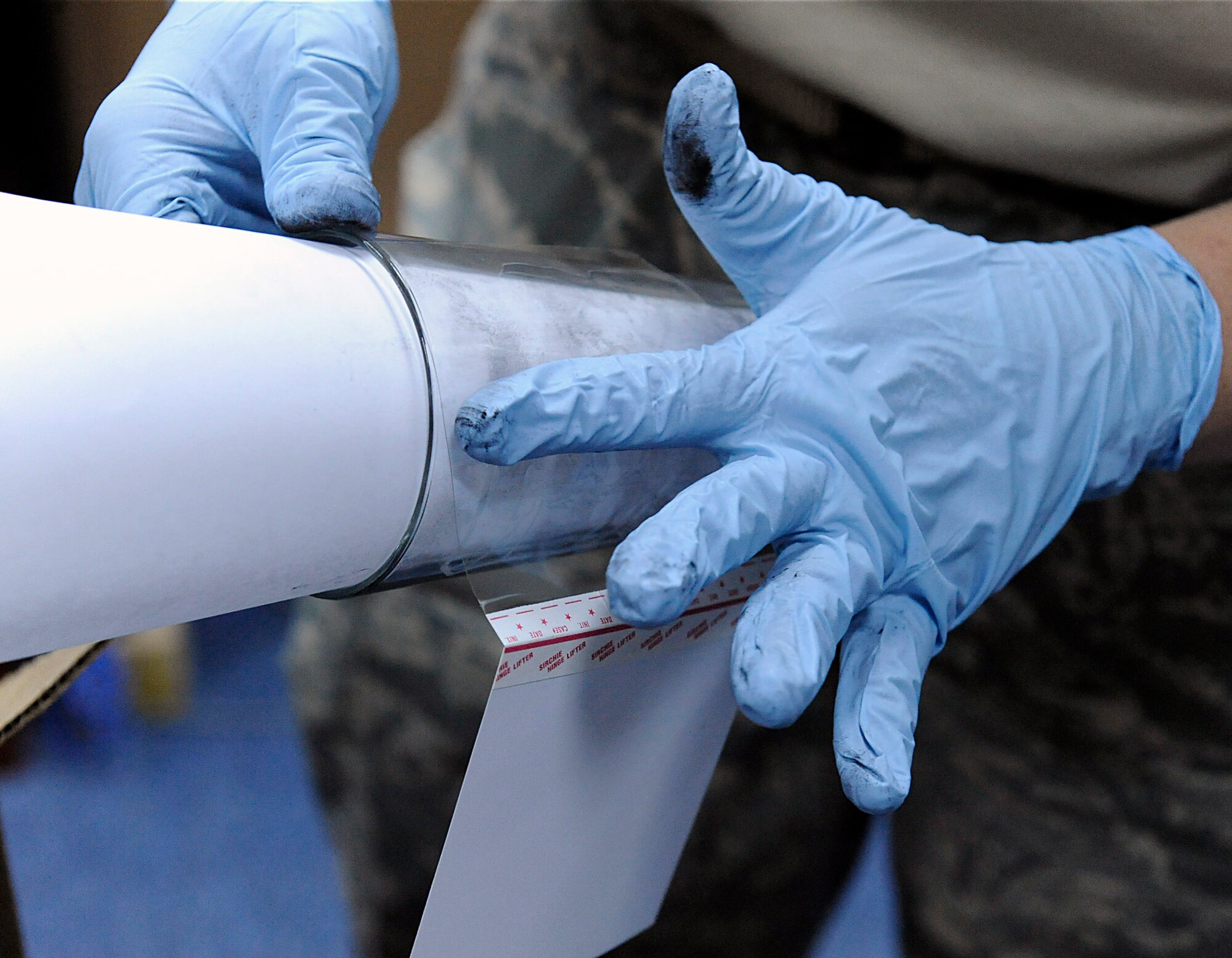 Tech. Sgt. Kathy Trim lifts fingerprints from a glass April 11 at an air base in Southwest Asia. Once the fingerprints are lifted from the glass, they are sent to a lab to be cross referenced for any possible "suspects." She is with the 380th Expeditionary Security Forces Squadron. (U.S. Air Force photo/Senior Airman Brian J. Ellis) 
