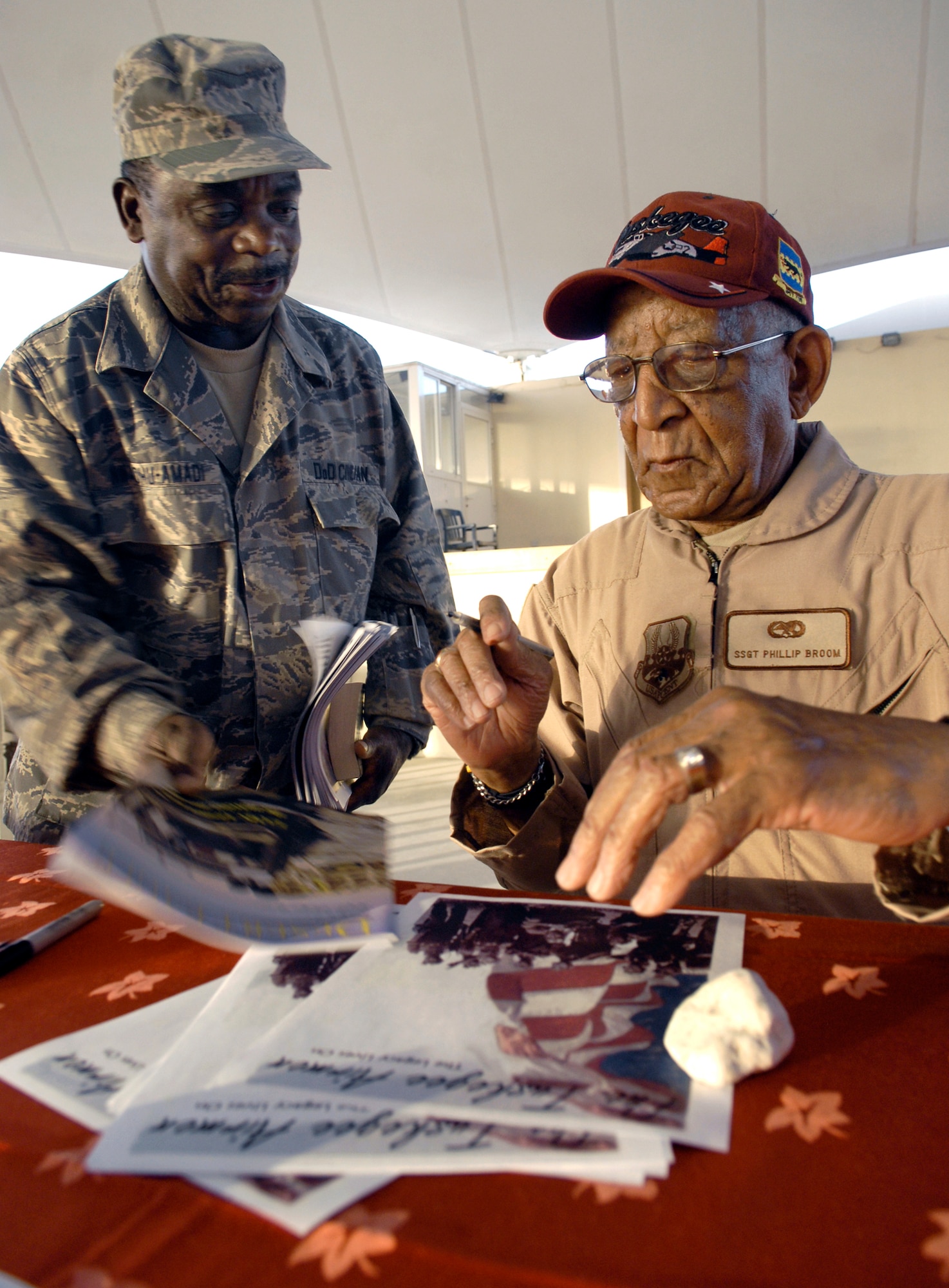 Tuskegee Airman Staff Sgt. Phillip Broom signs an autograph for Kasie Nwaohu-Amadi during a visit April 22 to a base in Southwest Asia.  Sergeant Broom was part of a group of Tuskegee Airmen touring the area of responsibility.  Mr. Nwaohu-Amadi is a chemist with the 379th Expeditionary Logistic Readiness Squadron, and deployed from Wright-Patterson Air Force Base, Ohio.  (U.S. Air Force photo/Senior Airman Andrew Satran)    