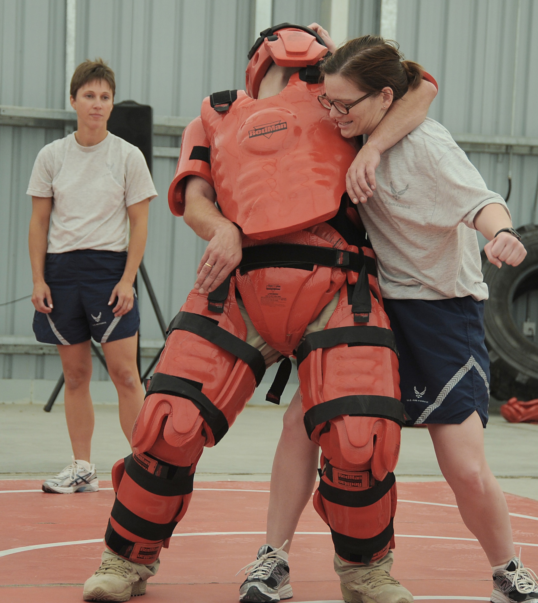 During self-defense training Capt. Kelly McElroy prepares to give a blow to the midsection of Rick Baldwin, a contractor posing as the "red man attacker," as Master Sgt. Malinda Kingsley watches April 18 at an air base in Southwest Asia. Captain McElroy is assigned to the 380th Expeditionary Communications Squadron, and Sergeant Kingsley is from the 380th Expeditionary Maintenance Squadron. (U.S. Air Force photo/Senior Airman Brian J. Ellis)