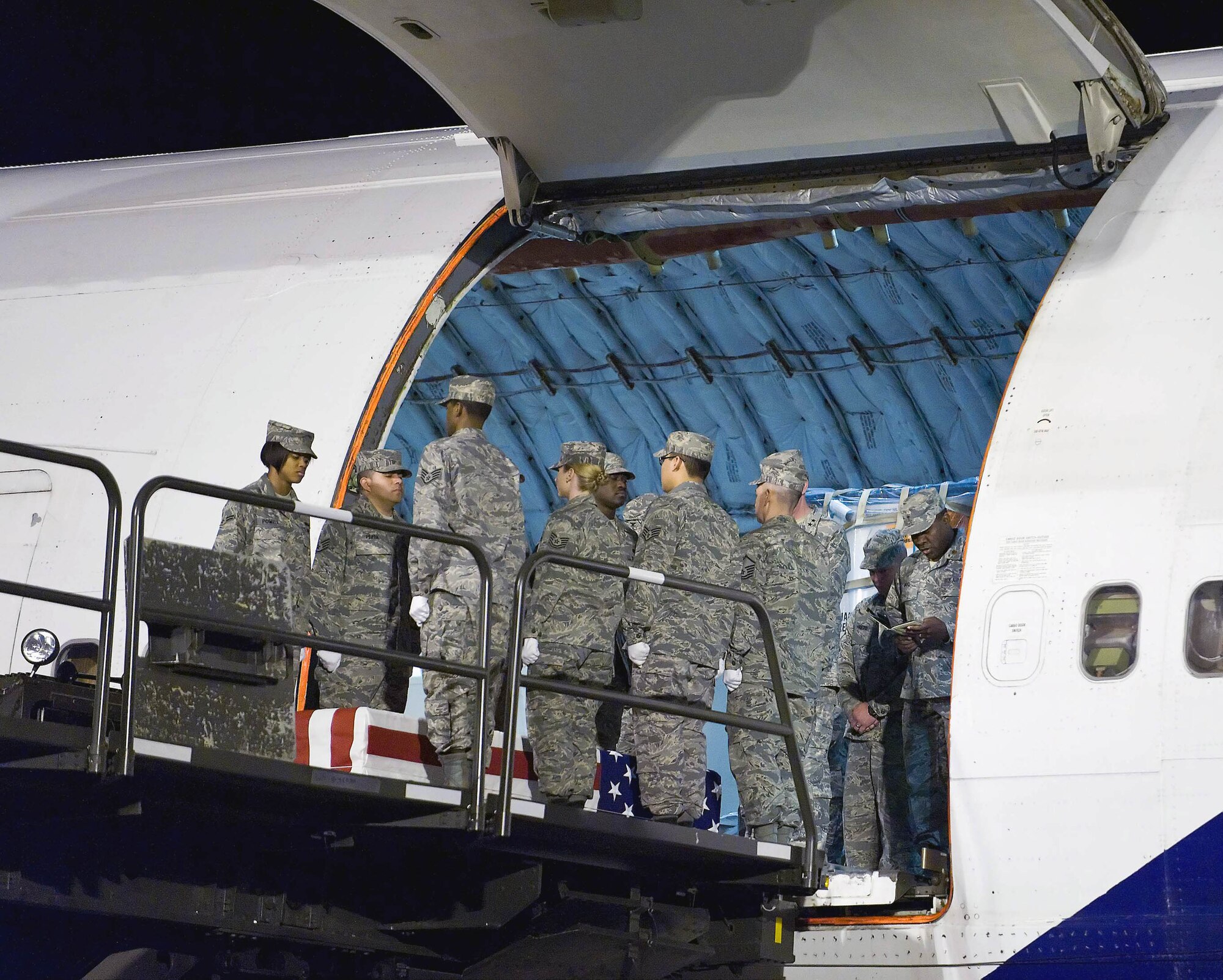 Chaplain (Maj.) Klavens Noel (far right) prays over remains on an aircraft at Dover Air Force Base, Del. Chaplain Noel is a port mortuary chaplain at the Air Force Mortuary Affairs Operations Center at Dover AFB. (U.S. Air Force photo/Roland Balik) 