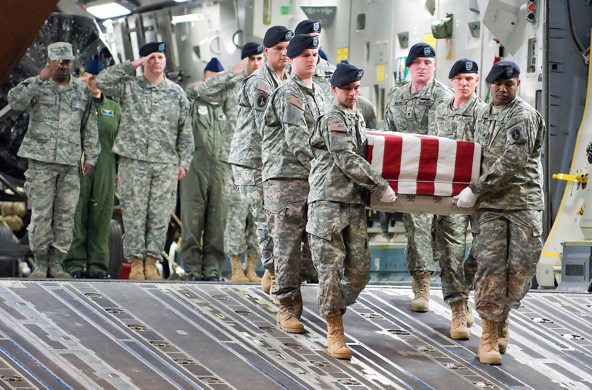 Chaplain (Maj.) Klavens Noel (far left) along with a senior Army and Air Force officers salute a transfer case as an Army carry team transfers remains at Dover Air Force Base, Del. After Defense Secretary Robert M. Gates approved a policy change in April allowing media filming of dignified transfer operations, more and more family members now attend the transfers.  Chaplain Noel is a port mortuary chaplain at the Air Force Mortuary Affairs Operations Center at Dover AFB. (U.S. Air Force photo/Roland Balik) 