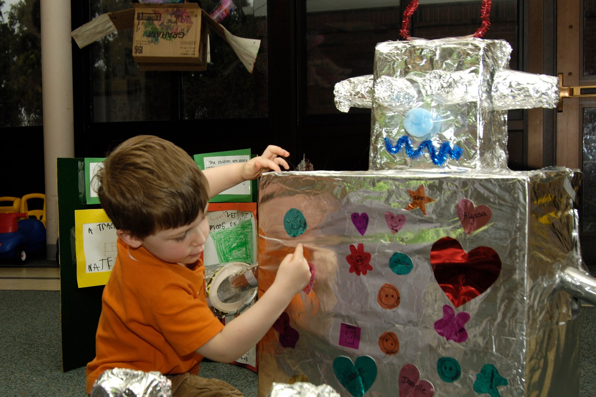 HANSCOM AIR FORCE BASE, Mass. – Matheson MacLeod adds some decorations to a robot that students in Room 8 at the Child Development Center assembled from recycled items. The activity was one of the Month of the Military Child events that the Center sponsored. (U.S. Air Force photo by Linda LaBonte Britt)