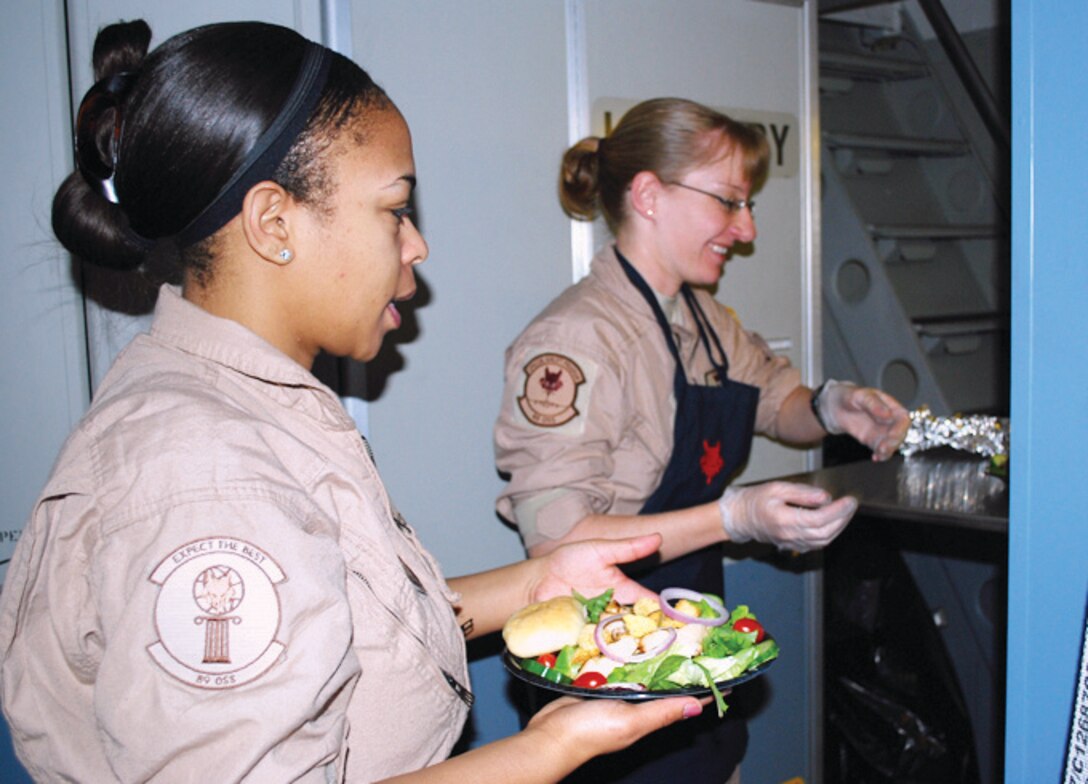 Staff Sgt. Jamiliah Austin-Graves and Tech. Sgt. Jennifer Lindner, 89th Airlift Wing, Operations Support Squadron, work together to keep the Air Force’s special passengers well fed and comfortable over places like Iraq and Afghanistan. They serve up a dinner fit for a king, president, general or anyone else who might be on the aircraft. (U.S. Air Force photo/ Major Bill Walsh)