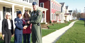 Colonel Steven Shepro, 316th Wing commander, gives the house key to Tech. Sgt. Tammy Butler, 779th Medical Operation Squadron physical medicine craftsman, with the support of Pam Sherouse, Liberty Park manager, left, and Karen Redman, Housing program manager, third from left, at Andrews April 17. The newly constructed houses are part of ongoing renovations of Andrews to enhance the quality of life for Airmen. (U.S. Air Force photo/ Senior Airman Giang Nguyen)