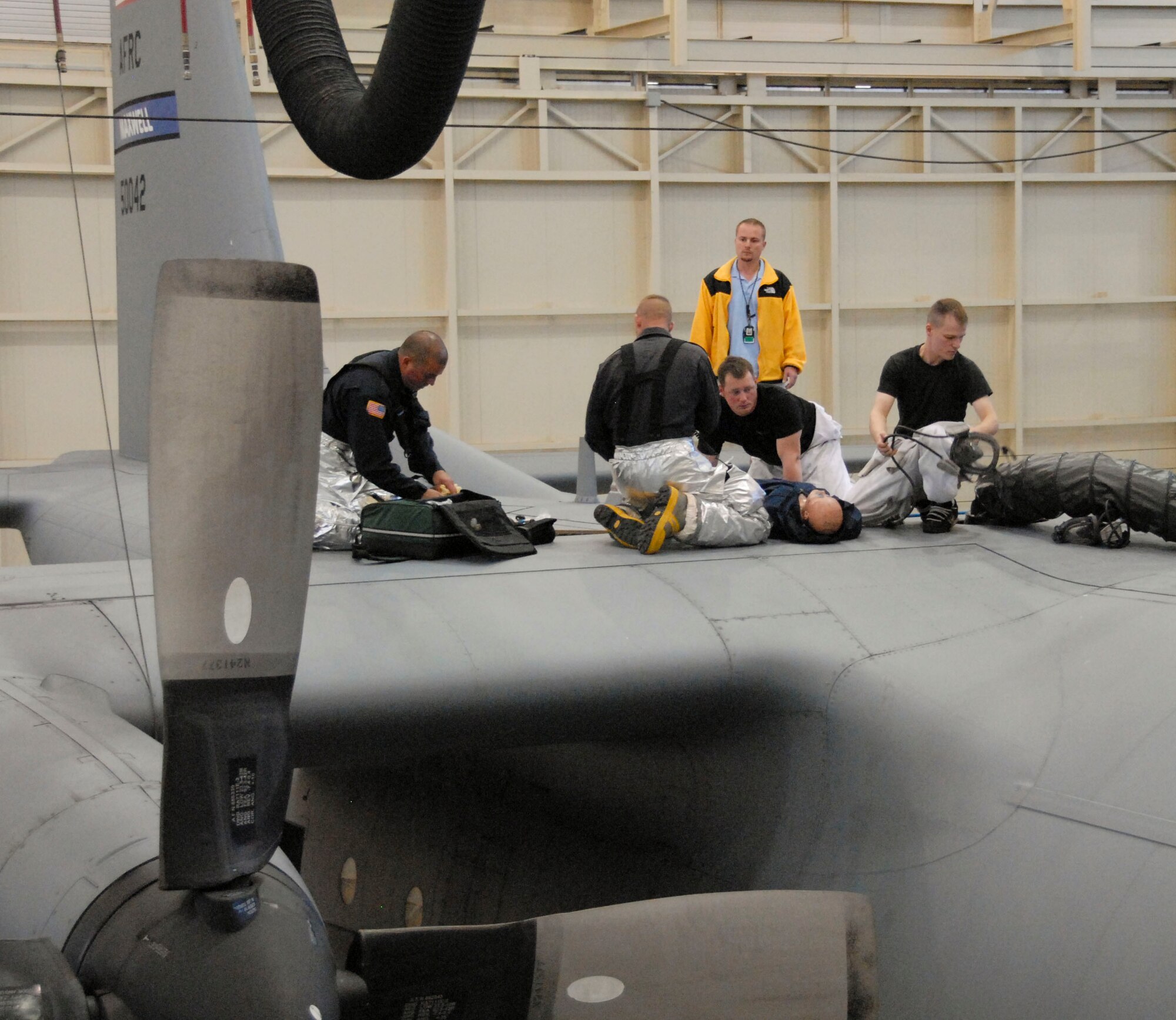 Members of the Maxwell Fire Department assist with the rescue of a 908th Airlift Wing aircraft maintenance member who passed out from fumes while inspecting the interior of a C-130 Hercules fuel tank. The scenario was part of the Maxwell-Gunter April base exercise. (U.S. Air Force photo by Jamie Pitcher)