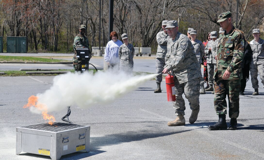 Tech. Sgt Matthew Anderson, 79th Medical Wing emergency medical response planner, extinguishes a fire under the supervision of Staff Sgt. Jeremy Bailey, 316th Civil Engineer Squadron training manager, during a recurrent fire prevention and extinguisher training for 79th Medical Wing command staff. (U.S. Air Force photo/ Tech. Sgt. Suzanne M. Day)
