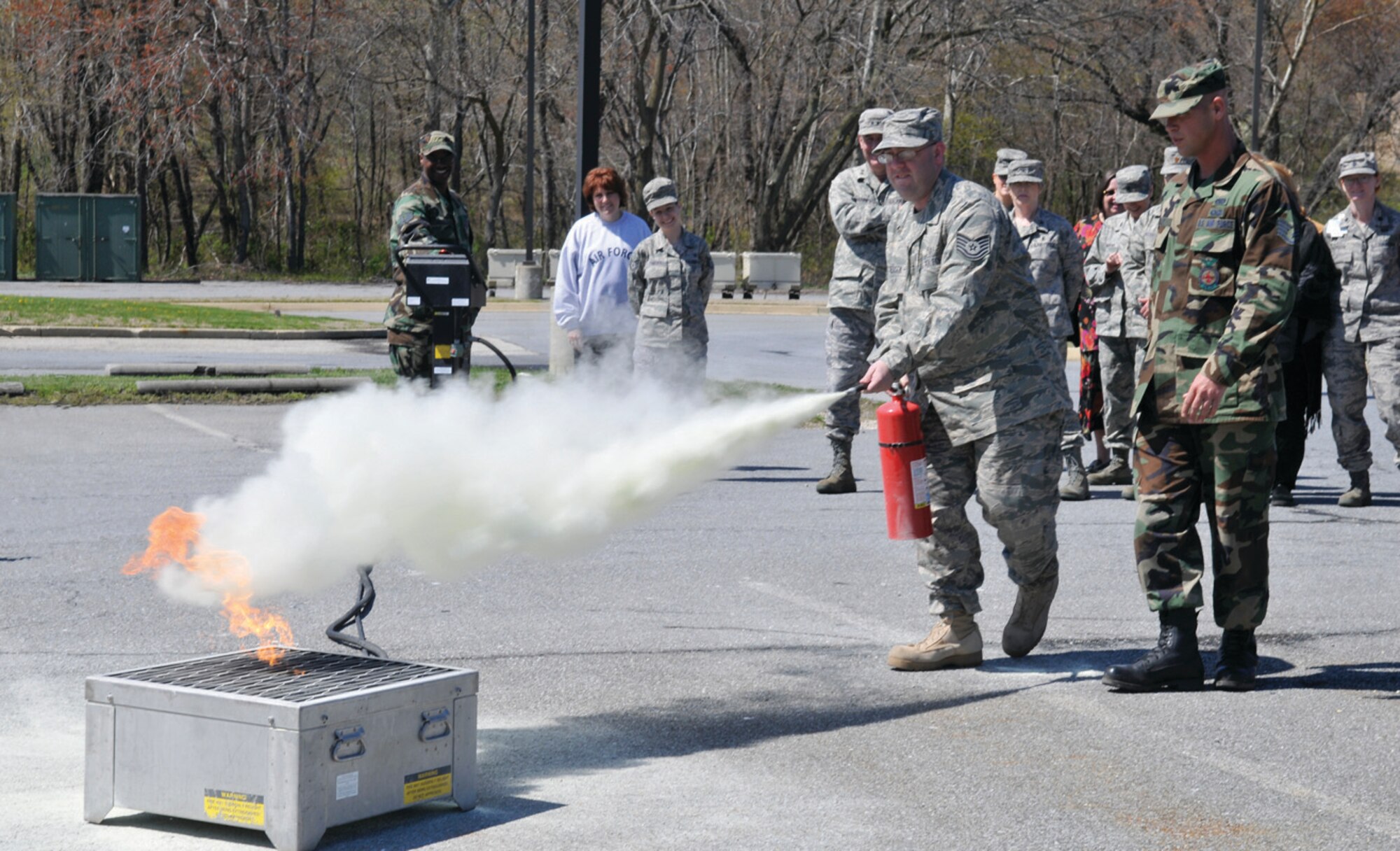 Tech. Sgt Matthew Anderson, 79th Medical Wing emergency medical response planner, extinguishes a fire under the supervision of Staff Sgt. Jeremy Bailey, 316th Civil Engineer Squadron training manager, during a recurrent fire prevention and extinguisher training for 79th Medical Wing command staff. (U.S. Air Force photo/ Tech. Sgt. Suzanne M. Day)