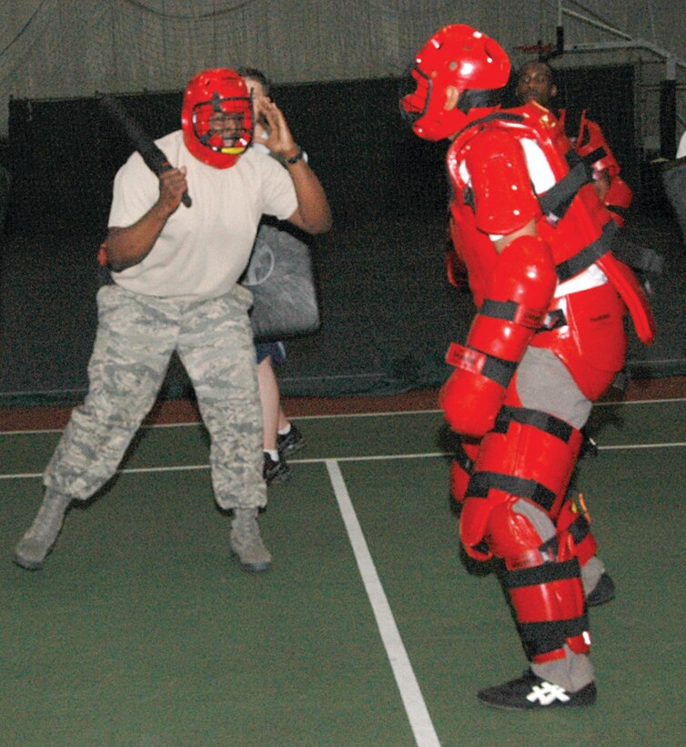 Technical Sgt. Rodrica Brown, left, 316th Security Forces Squadron Operations Support NCO, wards off attacker, Staff Sgt. Larry Logan, with a ASP expandable baton. Sergeant Logan, at right in a Redman padded suit, is a 316 SFS Raven apprentice. The security forces squadron members performed their annual ASP training during a four-hour period at the Tactical Fitness Center Tuesday. (U.S. Air Force photo/ Bobby Jones)