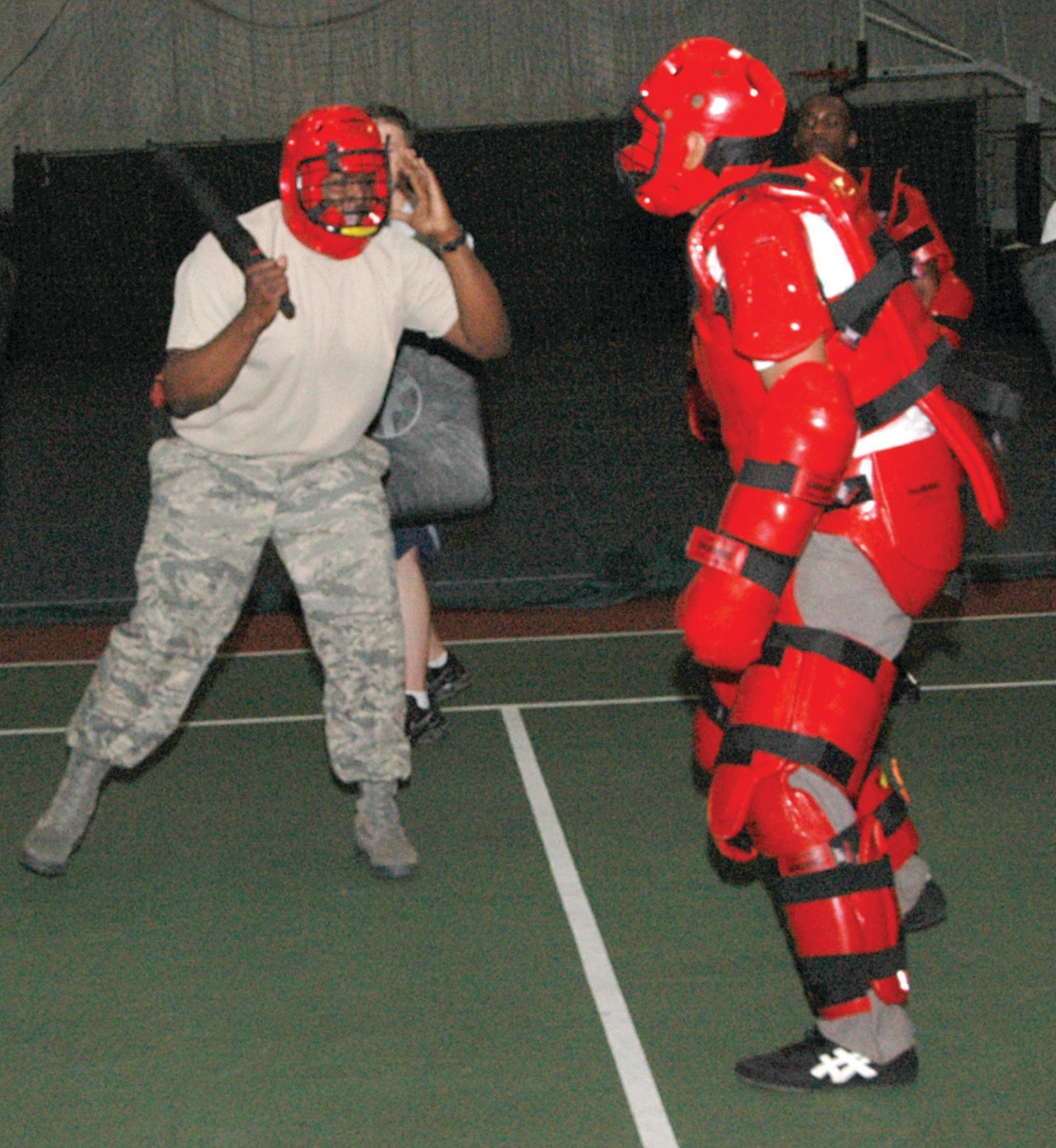 Technical Sgt. Rodrica Brown, left, 316th Security Forces Squadron Operations Support NCO, wards off attacker, Staff Sgt. Larry Logan, with a ASP expandable baton. Sergeant Logan, at right in a Redman padded suit, is a 316 SFS Raven apprentice. The security forces squadron members performed their annual ASP training during a four-hour period at the Tactical Fitness Center Tuesday. (U.S. Air Force photo/ Bobby Jones)