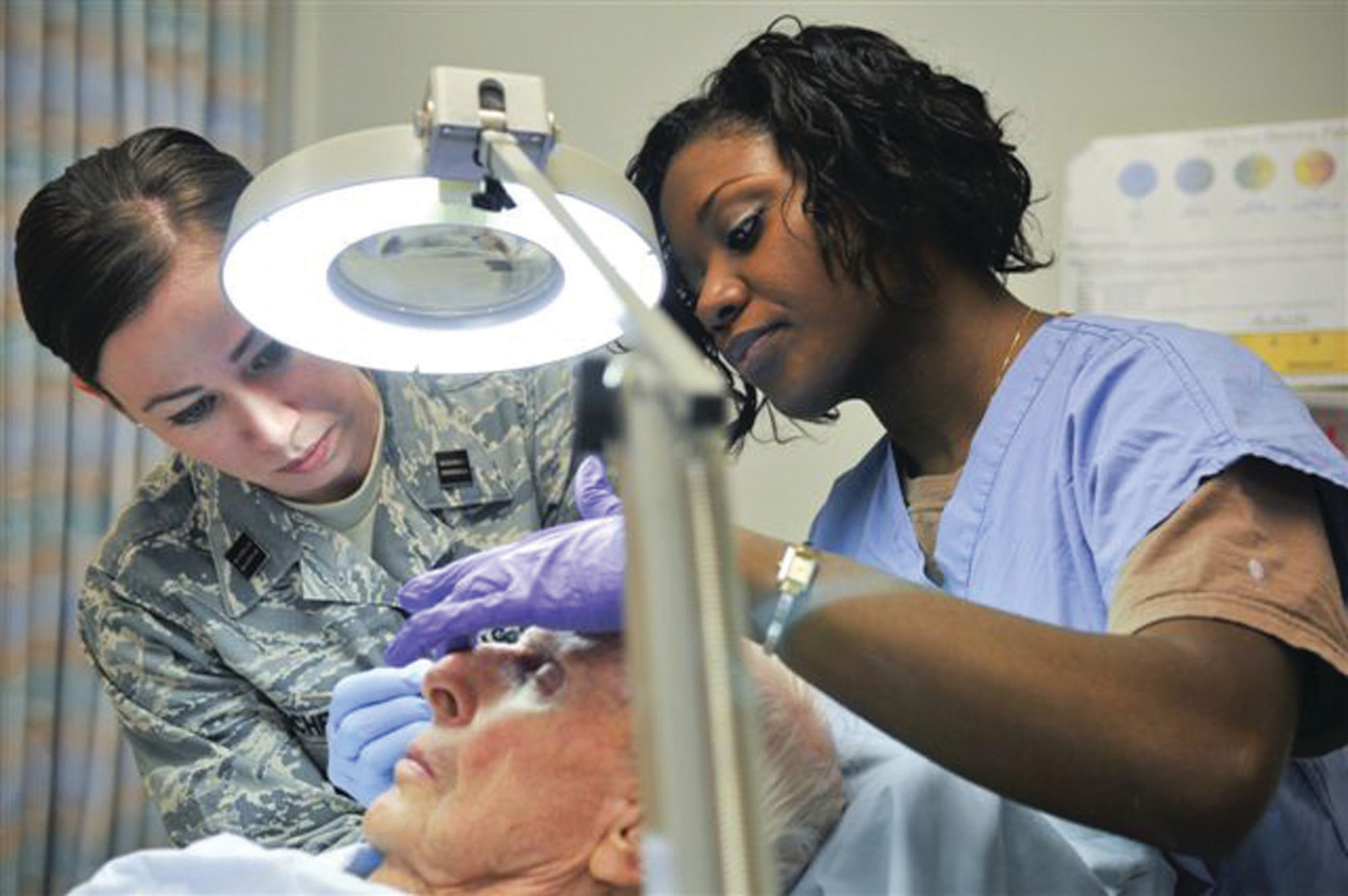 Physician's assistant student, Officer Trainee Ali Marchetti, left, assists Dr. Ronea Harris-Stith, 779th Medical Operations Squadron, in performing electrodesiccation and curettage for treatment of basal cell carcinoma of a patient at Malcolm Grow Medical Center. (U.S. Air Force photo/ Tech. Sgt. Suzanne M. Day)