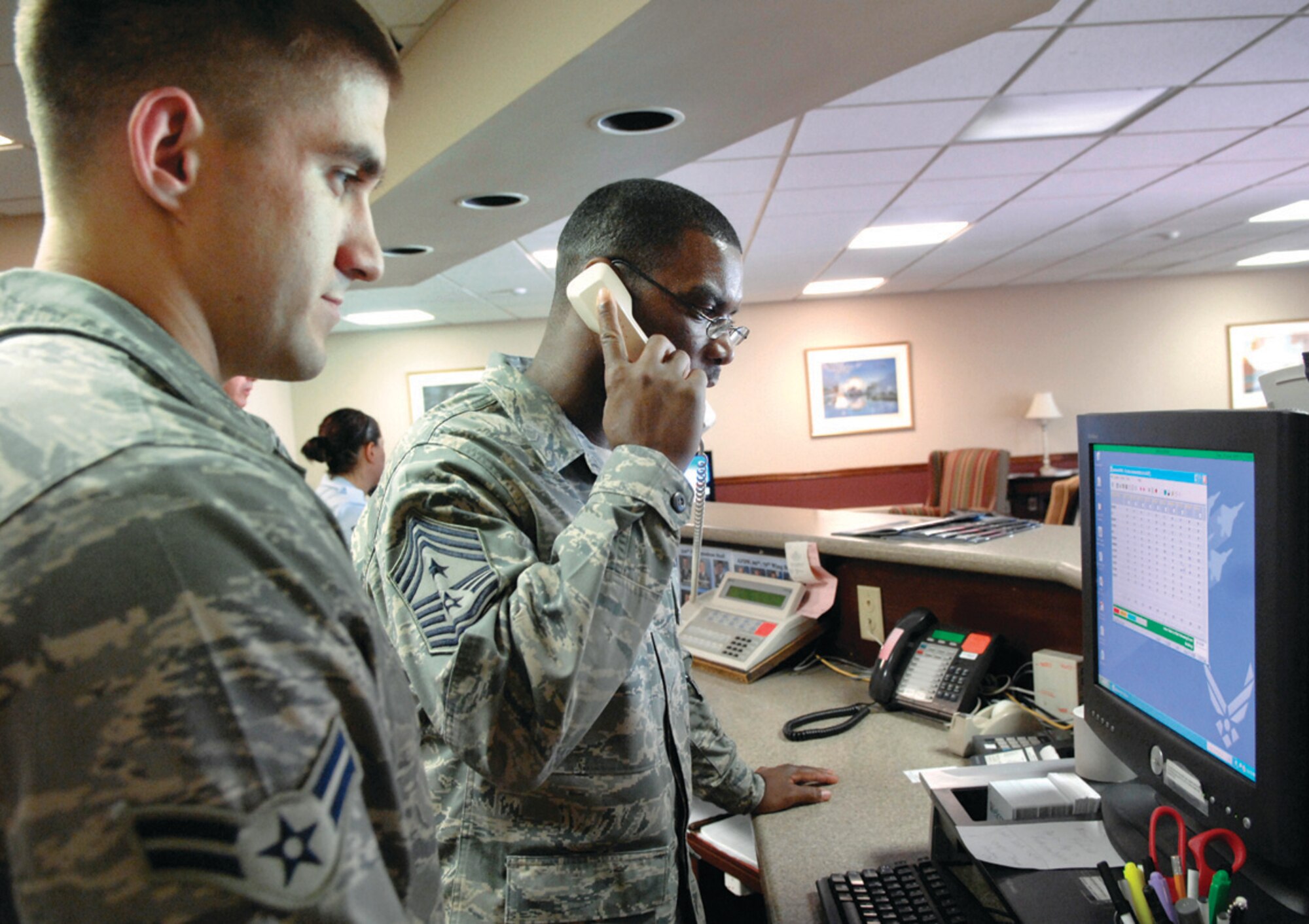 Chief Master Sgt. James Davis, 316th Wing command chief master sergeant, helps customers reserve a room over the phone, while Airman 1st Class Jonathan Howard, 316 FSS service representative, ensures quality assurance at the Gateway Inn. The 316 WG leadership goal is to understand the role and responsibilities of various jobs on base in order to maximize the potential of the Airmen through weekly tactical visits. (U.S. Air Force photo/ Senior Airman Giang Nguyen)