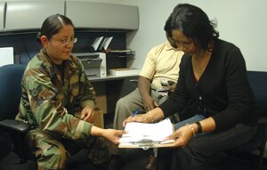 Airman 1st Class Mylia Phouamkha, 316th Force Support Squadron customer service representative at the Military Personnel Service flight, Bldg. 1414, gives guidance to Jean Ball-Thorne on where to sign her new spouse identification card as her husband, Master Sgt. (ret.) Art Thorne, observes Tuesday. (U.S. Air Force photo/ Bobby Jones)