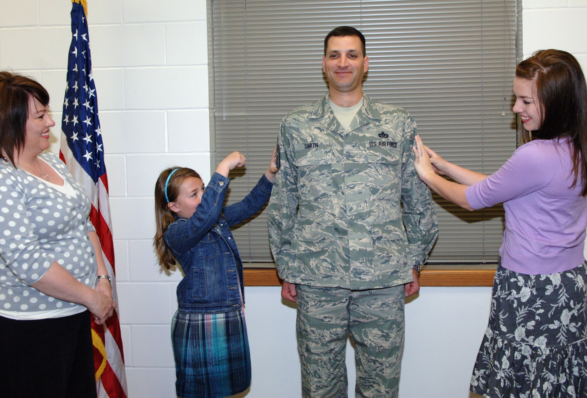 Kurt Smith's daughters, Reagan (on left) and Katelynn, tack on his chief master sergeant stripes during a promotion ceremony April 18. Chief Smith is also the new operations and maintenance chief of the 931st Civil Engineer Squadron, an Air Force Reserve unit at McConnell Air Force Base, Kan. Also pictured is the chief's wife, Rebecca. (U.S. Air Force photo/Senior Airman Connor Burkhard)
