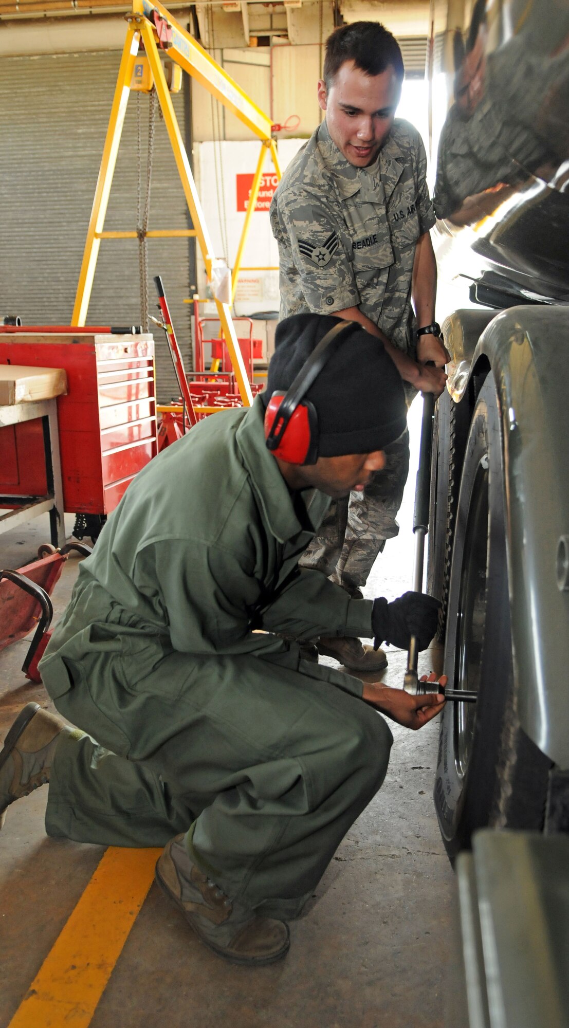 Airman Basic Brian Roy holds an over-sized socket wrench to the lug nut of one of the 100th Logistics Readiness Squadron fuels maintenance shop’s five new fuel trucks while Senior Airman Skyler Beadle works it loose.  Tires on new trucks have to be adjusted when they first arrive to ensure valve stems are properly aligned.  (U.S. Air Force photo by Staff Sgt. Austin M. May)