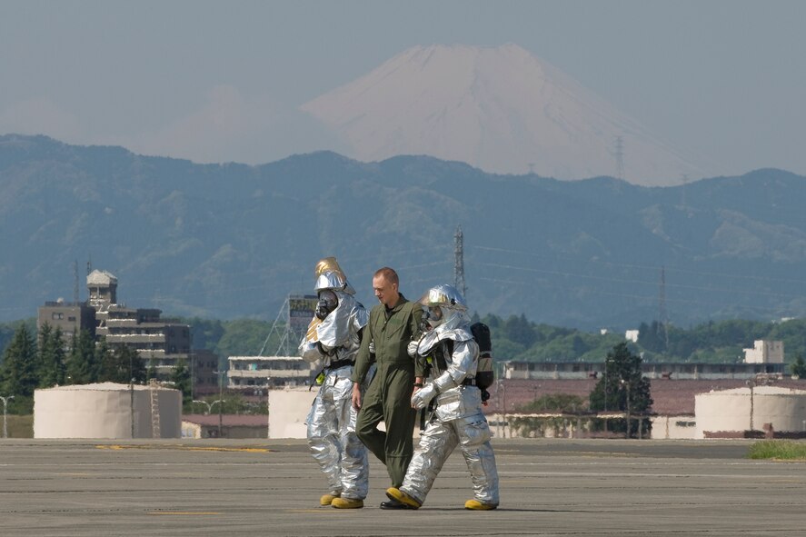 YOKOTA AIR BASE, Japan --  Base firefighters escort an aircrew member who walked away from his aircraft April 23 during an emergency management exercise. The wing's inspector general conducts regularly scheduled exercises to test the capabilities of base personnel to respond to a variety of possible accidents and incidents. (U.S. Air Force photo/Osakabe Yasuo)

