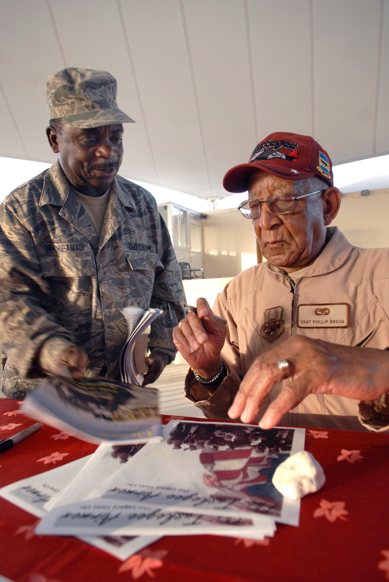Mr. Phillip Broome of the Tuskegee Airmen signs an autograph for Kasie Nwaohu-Amadi, a chemist with the 379th Expeditionary Logistic Readiness Squadron, during the Tuskegee Airmen's visit to the base, Apr. 22, 2009, at an undisclosed location in Southwest Asia.  Mr. Broome served as a Staff Sgt. during World War II as an engine mechanic with the Tuskegee Airmen.  Mr. Nwaohu-Amadi is native to Dayton, Ohio and is deployed from Wright-Patterson Air Force Base, Ohio.  The Tuskegee Airmen toured operations and spoke with numerous personnel here supporting Operations Iraqi and Enduring Freedom and Combined Joint Task Force - Horn of Africa on base sharing their stories and history when they served in the military.  (U.S. Air Force photo/Senior Airman Andrew Satran/released)    
