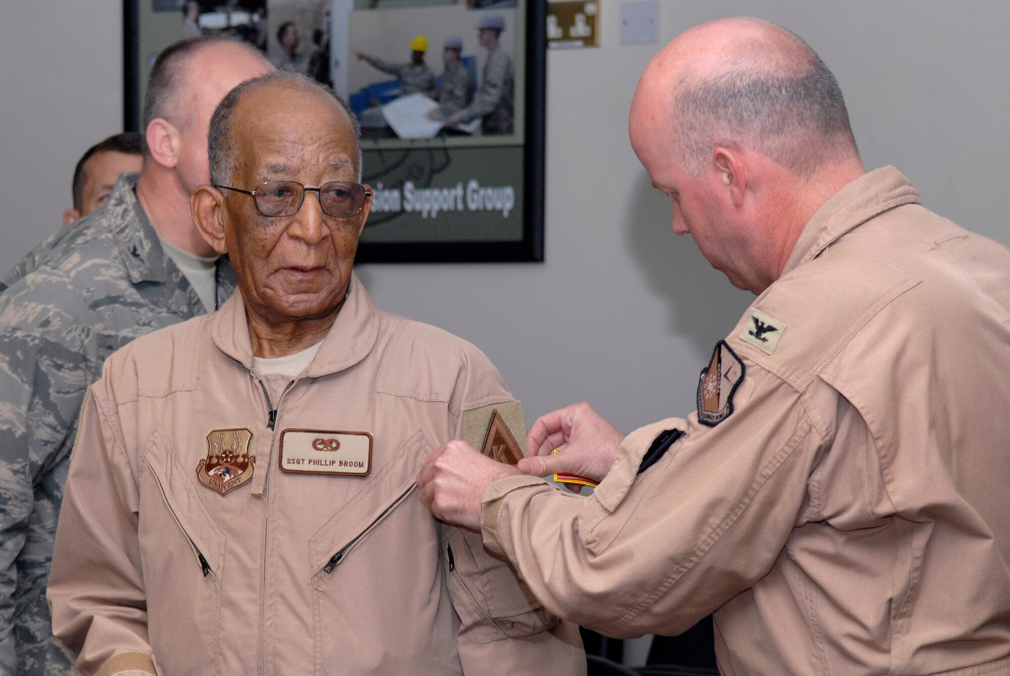 379th Air Expeditionary Wing Vice Commander, Colonel Paul Guemmer, puts a wing Traingle K patch on Mr. Philip Broom of the Tuskegee Airmen during his visit of the base, Apr. 22, 2009, at an undisclosed location in Southwest Asia.  Mr. Broom served as a Staff Sgt. during World War II as a jet engine mechanic with the Tuskegee Airmen.  The Tuskegee Airmen toured operations and spoke with numerous personnel here supporting Operations Iraqi and Enduring Freedom and Combined Joint Task Force - Horn of Africa on base sharing their stories and history when they served in the military.  (U.S. Air Force photo/Senior Airman Andrew Satran/released)    