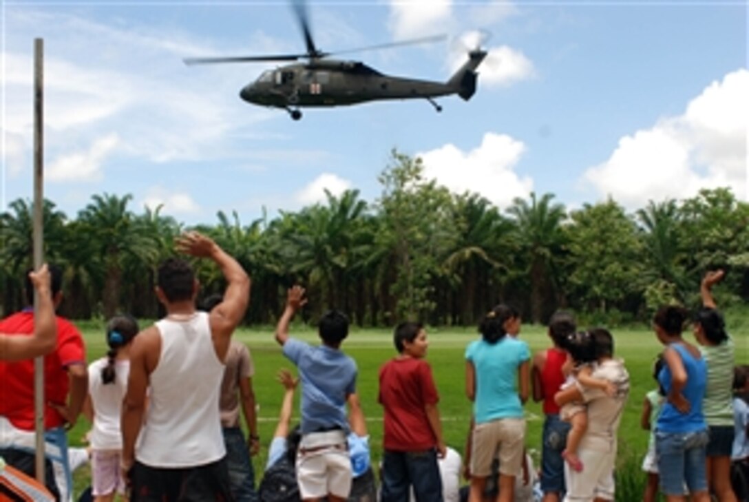 Residents of Silencio, Costa Rica, wave to a helicopter carrying members of the New Mexico Army National Guard Medical Detachment and Air Force South, which provided a full day of health-care services, April 23, 2009. A Costa Rican dental team, pharmacy technicians, internal medicine doctors and preventive health specialists participated in the event. This was the first time the National Guard's State Partnership Program has been used in a disaster relief exercise in a foreign country.