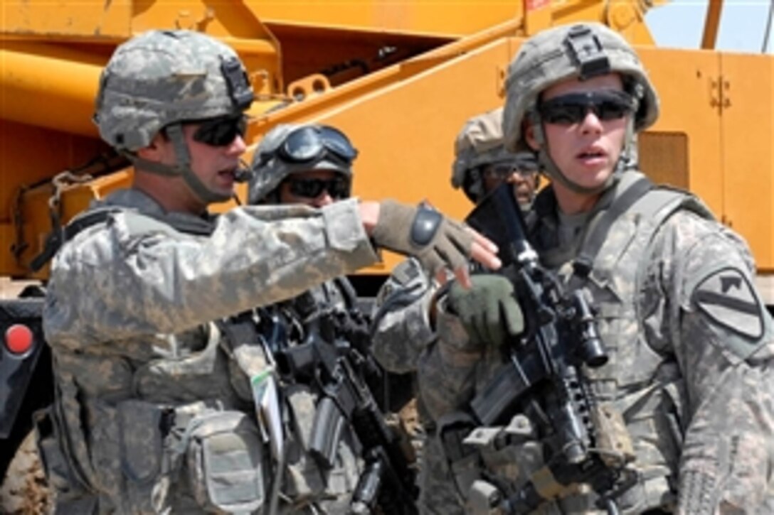U.S. Army 1st Lt. Aaron Shittack, left, and Cpl. Thomas Robbins, right, access progress in building barriers to provide security to a national police station in Husseniyah, Iraq, April 19, 2009. Shittack is a platoon leader and Robbins is a medic in the 1st Cavalry Division's Troop B, 1st Squadron, 7th Cavalry Regiment.