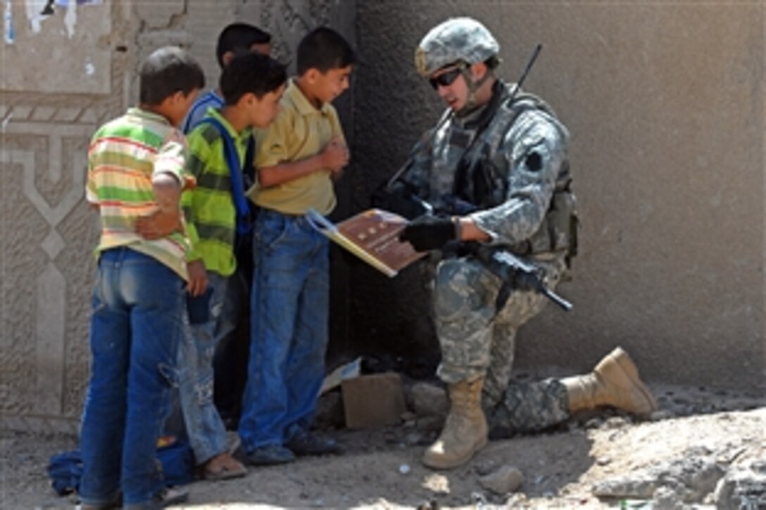U.S. Army Spc. John Dufrene reads from an English book to Iraqi school children outside the Eserah School in Nassir Wa Salam, Iraq, April 19, 2009. Dufrene is assigned to the 1st Infantry Division, 2nd Brigade, which is overseeing repairs and structural improvements to schools throughout the Nassir Wa Salam province.