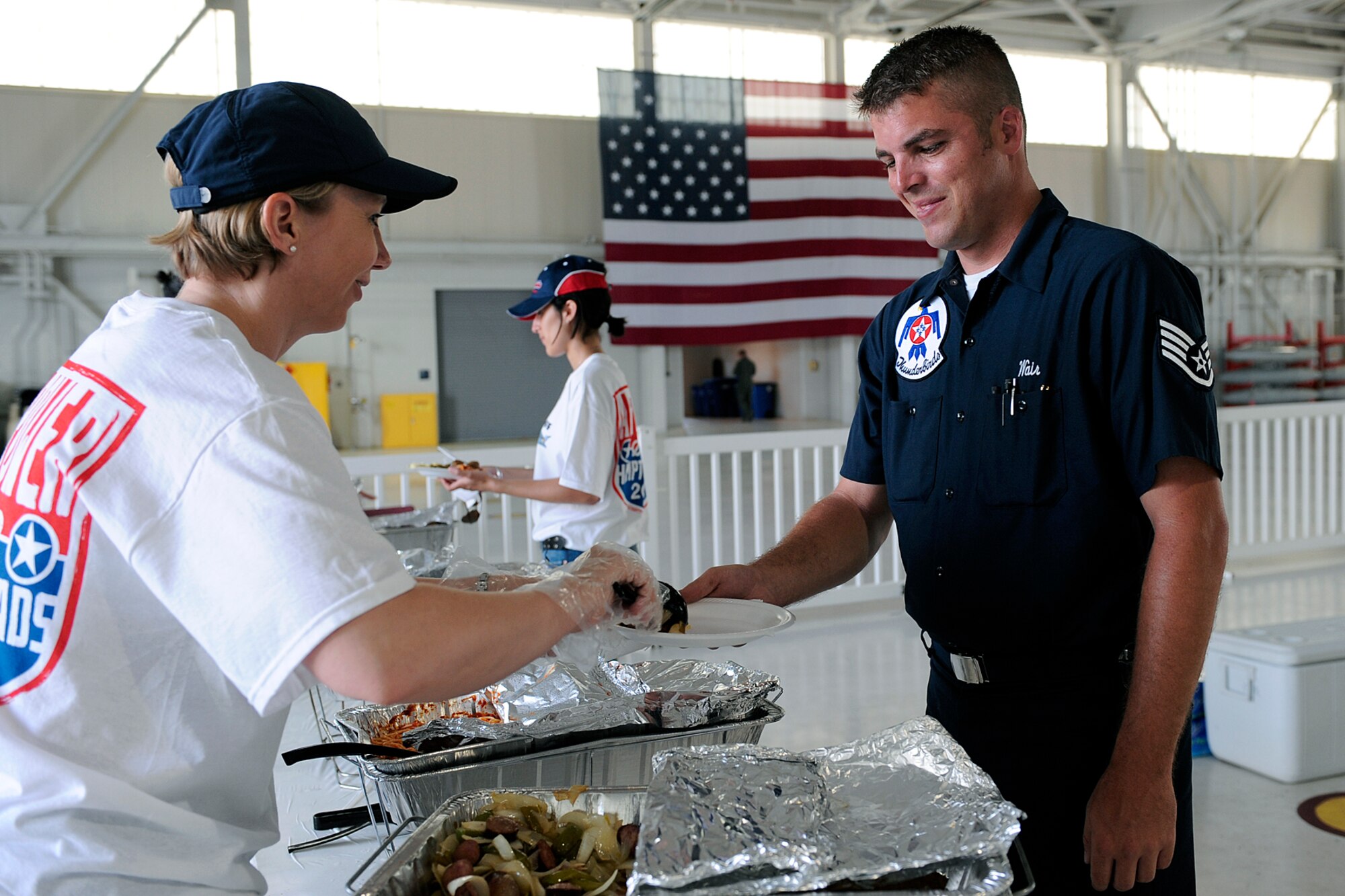LANGLEY AIR FORCE BASE, Va. -- Senior Master Sgt. Jennifer Kirsch, Headquarters Air Combat Command Personnel Dirctorate, serves food to Staff Sgt. Timmothy Wair, Thunderbirds plans and scheduling specialist, during AirPower over Hampton Roads open house here April 25.  This annual event helps educate the public on Air Force capability, increase recruiting and show appreciation to the local community.  (U.S. Air Force photo) 