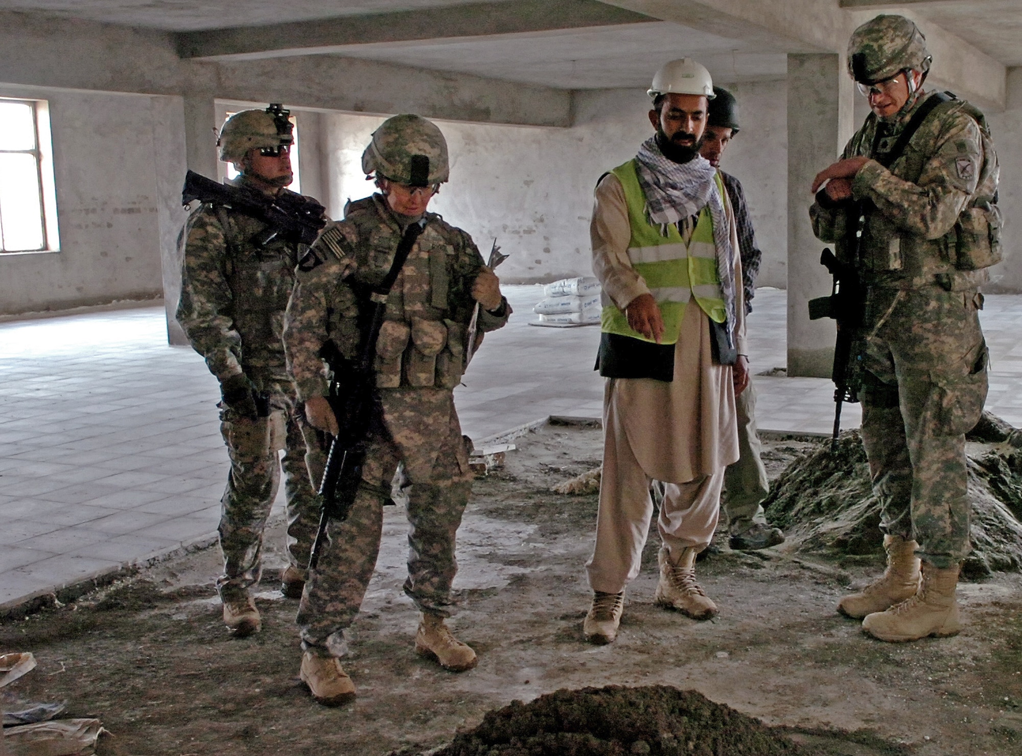 A construction contractor of the Gardez Center of Educational Excellence explains the materials used to build the dining facility to Lt. Col. Daniel Moy, Paktya Provincial Reconstruction Team commander, and Maj. Kimberly Riggs, Paktya PRT engineering officer-in-charge, during a recent quality assessment visit.