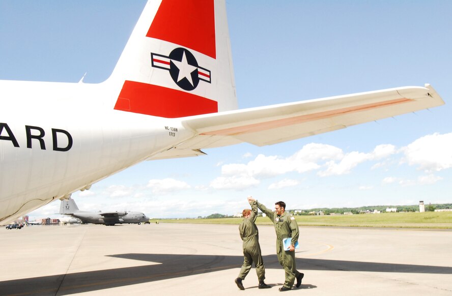 YOKOTA AIR BASE, Japan -- Lt. Cmdr. Brust Roethler, aircraft commander, (left) and Lt. Andrew Paszkiewicz, co-pilot, based at U.S. Coast Guard Air Station Barbers Point, Hawaii, celebrate a successful pre-flight inspection of their HC-130 Hercules Long Range Surveillance Aircraft April 26 before departing here to participate in the Japanese Coast Guard's Sea Review and Comprehensive Drill in Tokyo Bay. (U.S. Air Force photo/Master Sgt. Matt Summers) 