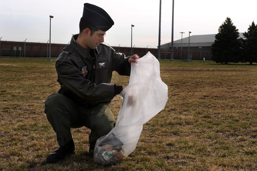 OFFUTT AIR FORCE BASE, Neb. - 1st Lt. Erik Martin, 38th Reconnaissance Squadron, places a piece of trash into a trash bag during base cleanup here April 10.  Members of the 55th Wing participated in the annual base cleanup by policing the areas around their work centers. U.S. Air Force Photo by Josh Plueger