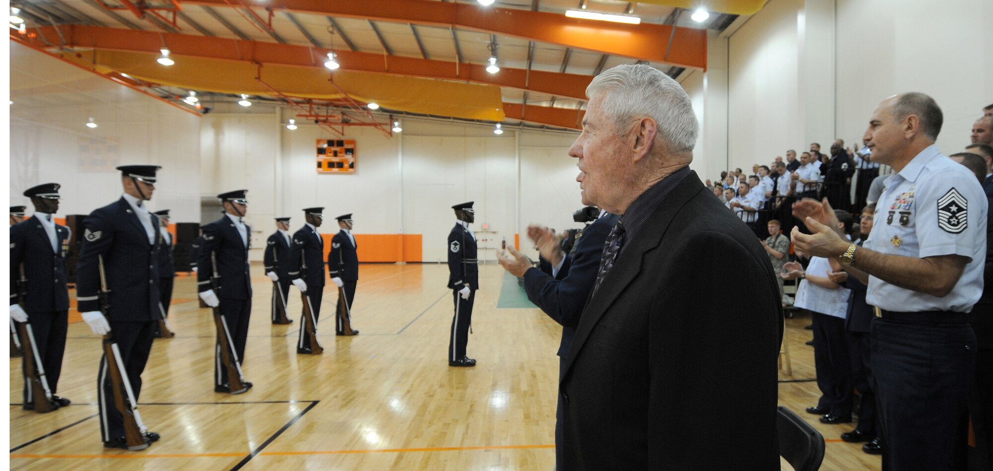 Fifth Chief Master Sergeant of the U.S Air Force Robert Gaylor watches The U.S Air Force Honor Guard Drill Team performs along withThe U.S Air Force Band's rock band "Max Imapact" after his opening speech 20th April Boo Sportsplex Hampton, Va. In retired Chief Gaylor’s speech he commented on The Band of Sisters, his time during WWII, the Vietnam war, and where our Airman are now during Air Force weeks Honoring America’s Veterans Ceremony. (U.S. Air Force photo by Senior Airman Alexandre Montes)