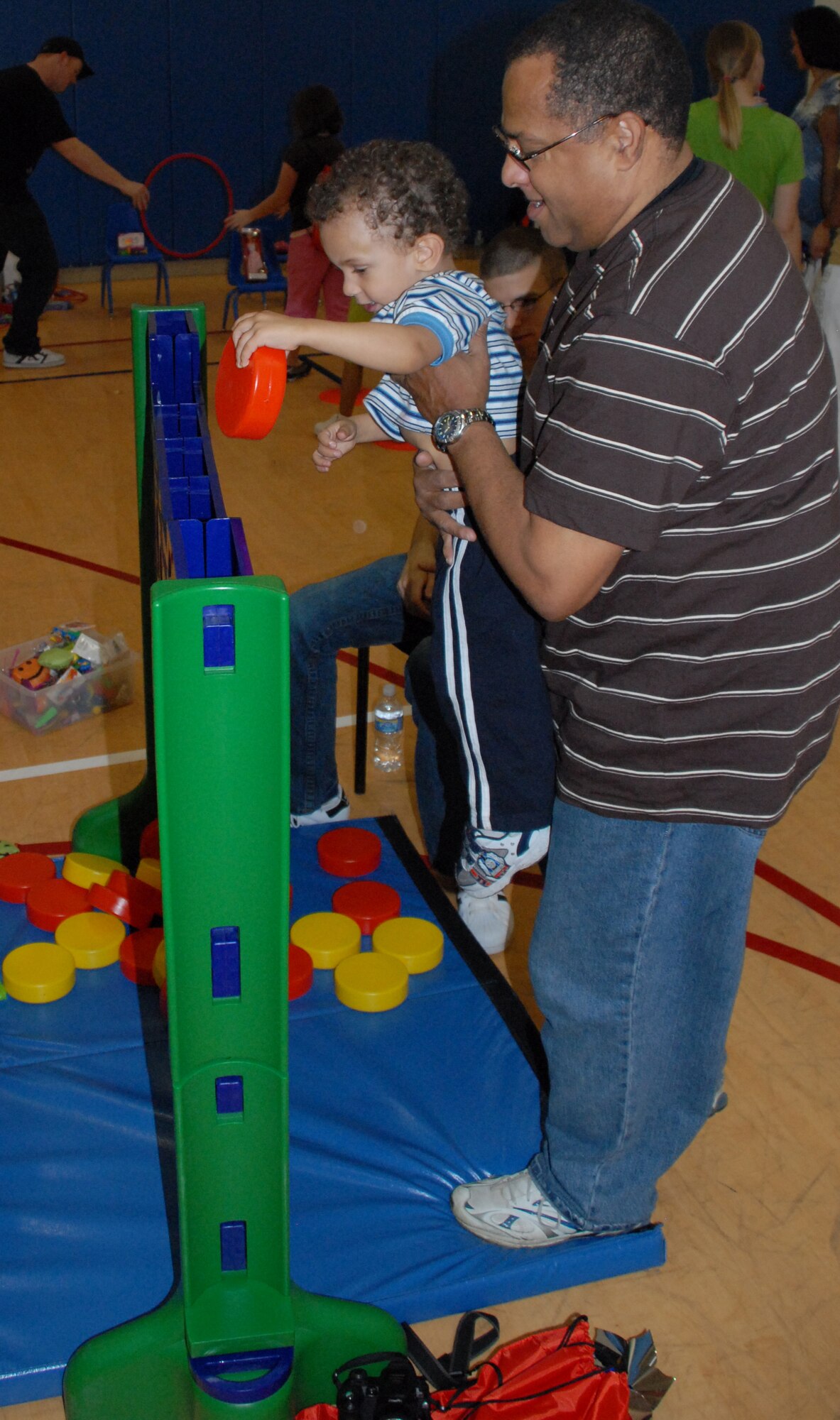 Master Sgt. (ret.) Tony Lee helps his 2 year-old grandson, Anthony Lee, play a game at the Childrens Carnival held at the Dover Air Force Base Youth Center April 18.  (U.S. Air Force photo/Staff Sgt. Chad Padgett)