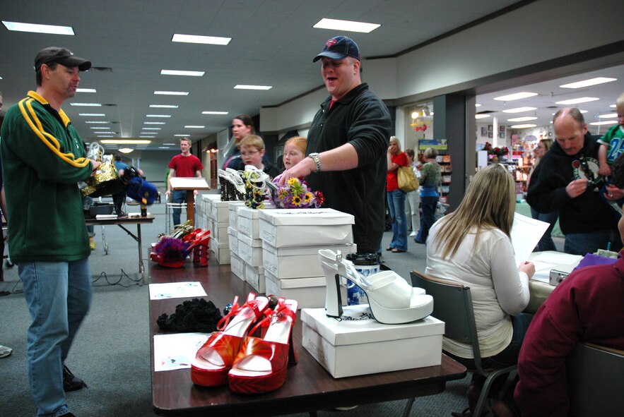 MINOT, N.D. -- Master Sgt. John Jeziorske, 5th Medical Operations Squadron mental health flight chief (center) picks out his high heels during a "walk a mile in her shoes" event at the Town and Country Mall here April 26. The event was designed to raise awareness of sexual assault. (U.S. Air Force photo by Senior Airman Wesley Wright)