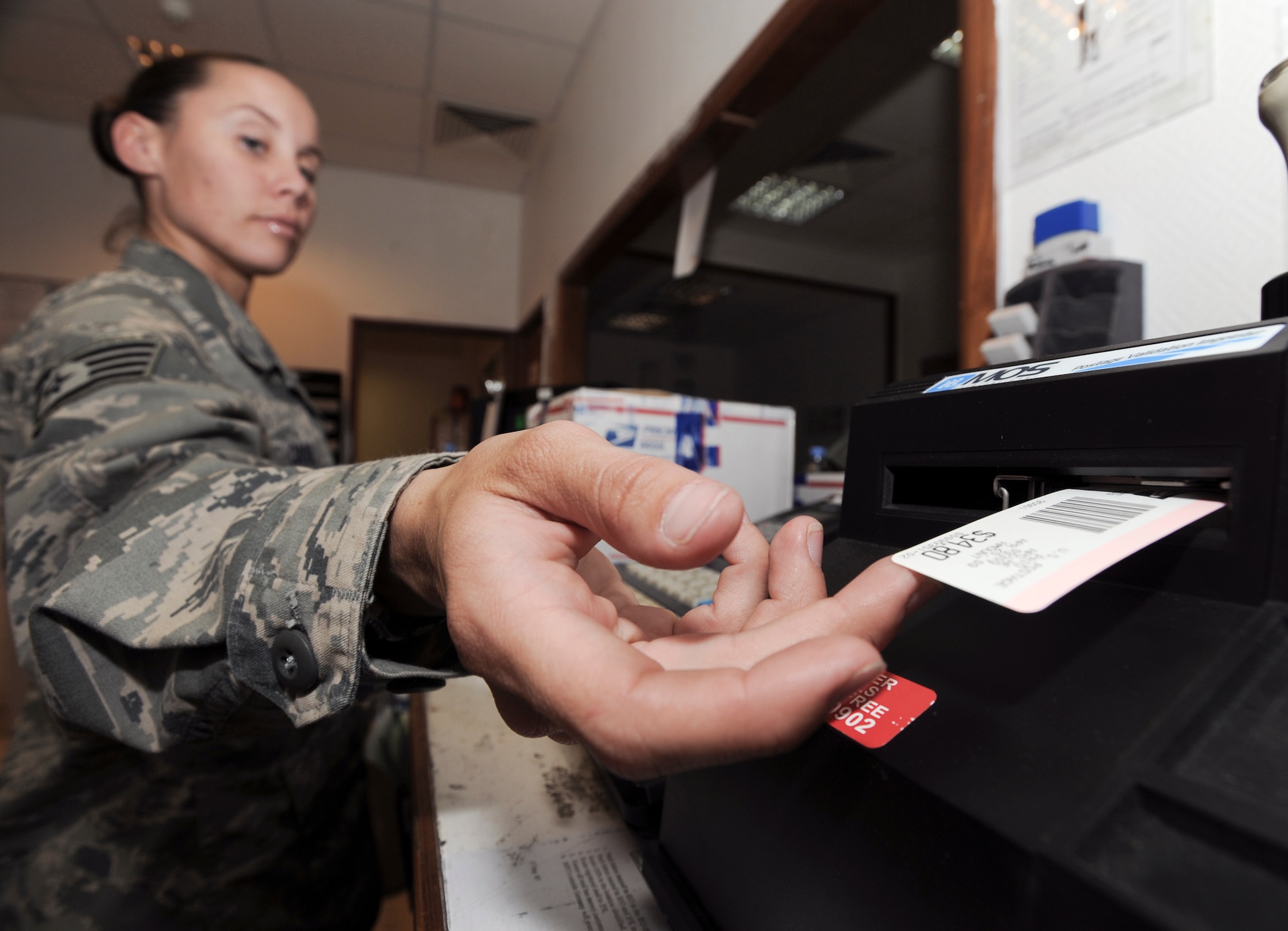 Staff Sgt. Cassandra Casul reaches for a price barcode after weighing a customer's package April 20 at an air base in Southwest Asia. Sergeant Casul and fellow postal clerks handle all outgoing mail for the base. Sergeant Casul is a 379th Expeditionary Communications Squadron postal clerk. (U.S. Air Force photo/Staff Sgt. Joshua Garcia) 
