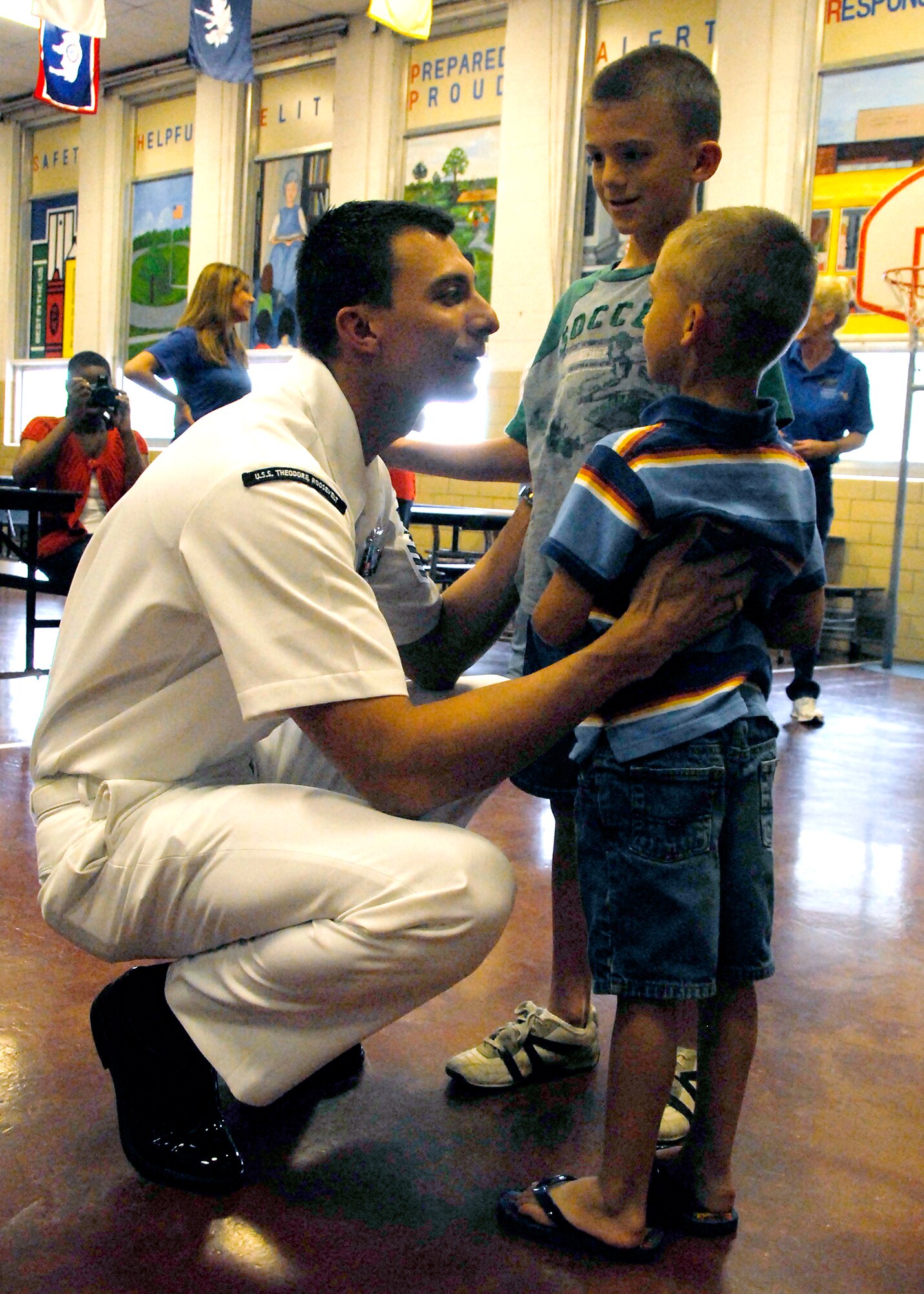 Petty Officer 1st Class Joe Salas, of the U.S.S. Theodore Roosevelt, reunites with his sons at Sheppard Elementary April 24, after a seven-month deployment to Iraq.  Nathan, 7, and Colby, 5, were called out of class and surprised by their father, who was waiting for them in the school cafeteria. (U.S. Air Force photo/ Mike Litteken)