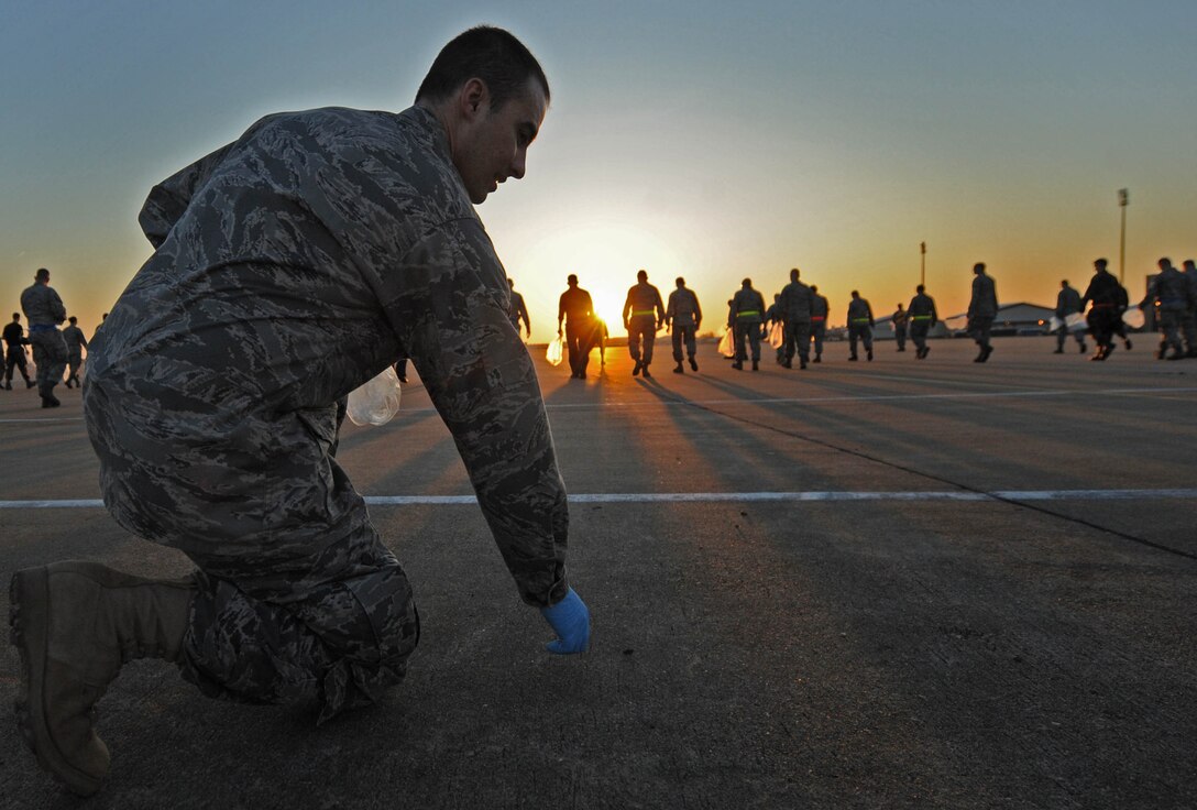 LANGLEY AIR FORCE BASE, Va. -- Airman 1st Class Travis Gregory, 27th Aircraft Maintenance Unit, picks up foreign object debris on the flightline April 27. The post-air show FOD walk was used to eliminate debris left behind from the fun filled weekend. (U.S. Air Force photo/Airman Rebecca Montez)