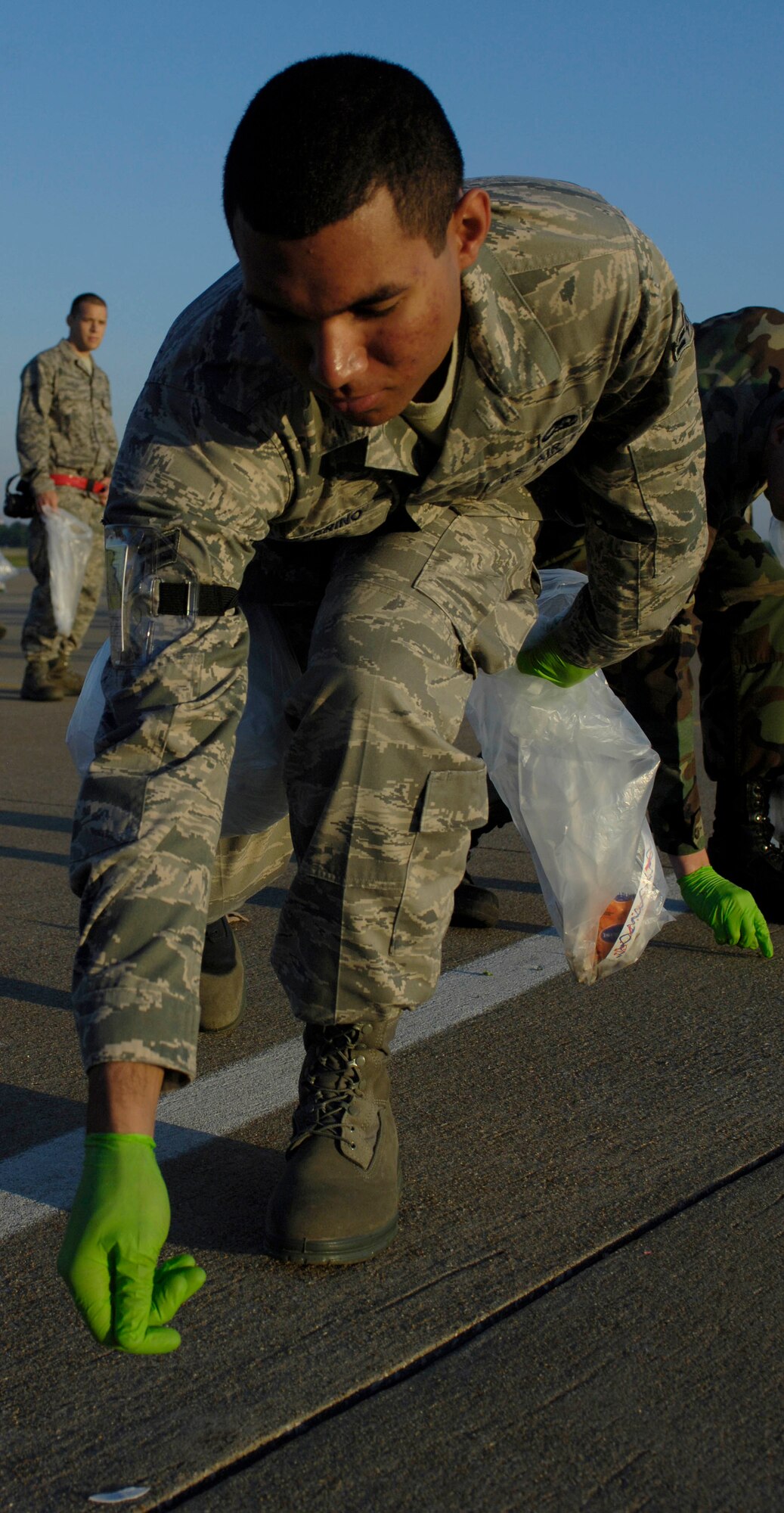 LANGLEY AIR FORCE BASE, Va. -- Airman 1st Class John Severino, 27st Aircraft Maintenance Squadron, picks up foreign object debris on flightline April 27. The post-air show FOD walk was used to eliminate debris left behind from the fun filled weekend. (U.S. Air Force photo/Airman Rebecca Montez)