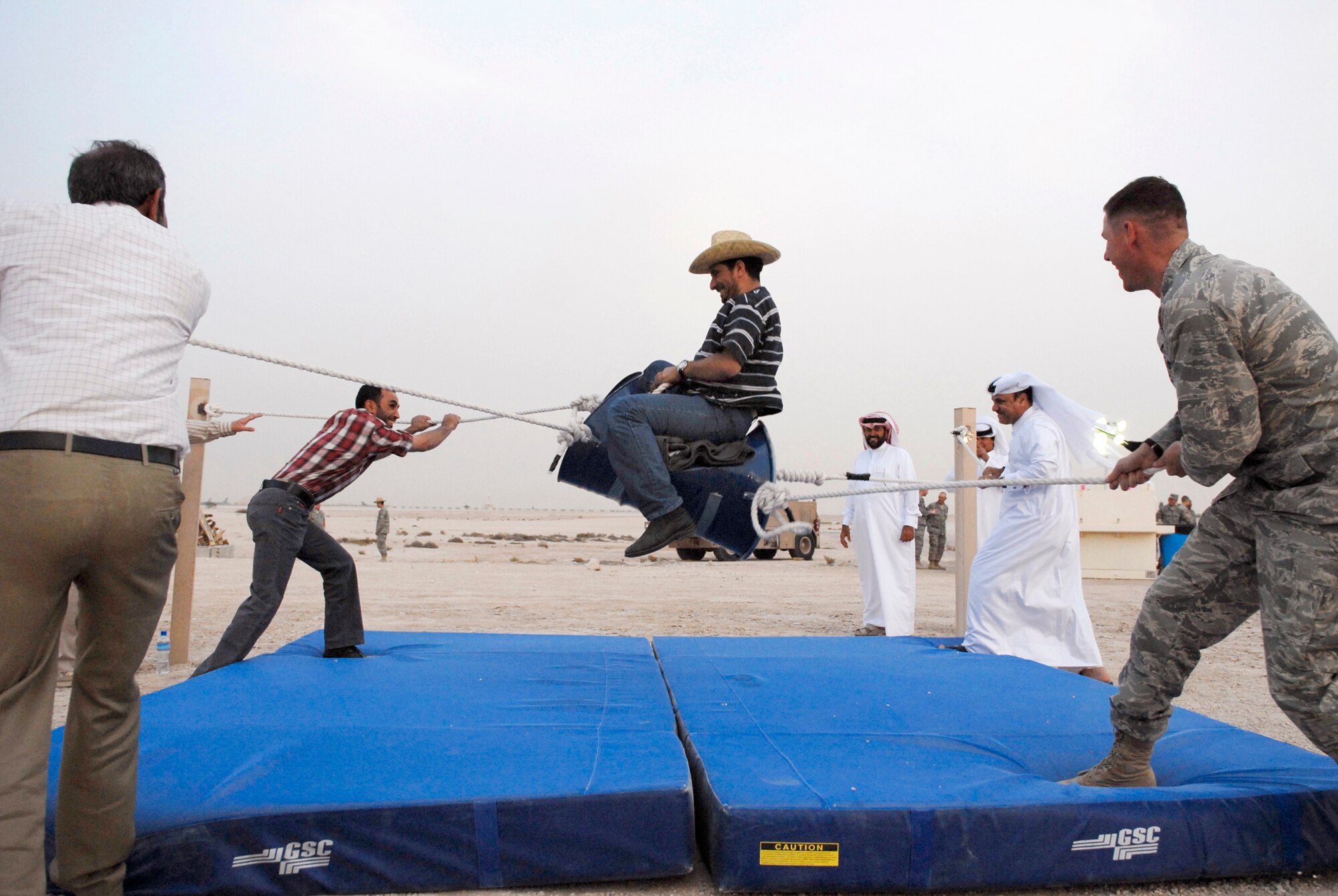 Host nation guests and a US Air Force Airman help provide the bucking for the mock mechanical bull ride during the Texas Style barbeque cultural event hosted by the 379th Air Expeditionary Wing, April 23, 2009, at an undisclosed location in Southwest Asia.  During the event coalition members and host nation guests participated in throwing horseshoes and a lasso, riding a mock mechanical bull, and eating Texas style food, to share some American culture.  The servicemembers who participated in this event are deployed in support of Operations Iraqi and Enduring Freedom and Combined Joint Task Force - Horn of Africa.  (U.S. Air Force photo/Senior Airman Andrew Satran/released)