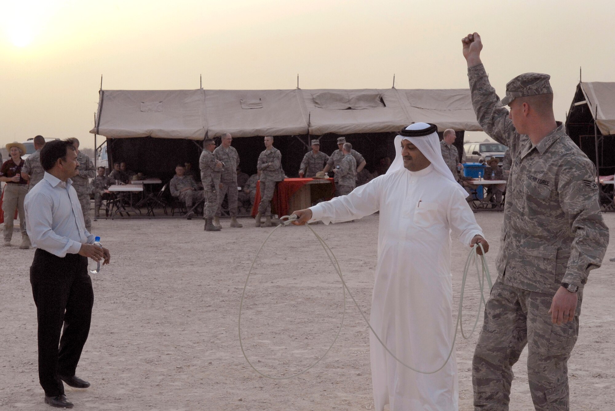 Senior Airman George Reves, from the 379th Expeditionary Maintenance Squadron, instructs a host nation guest in how to throw a lasso during the Texas Style barbeque cultural event hosted by the 379th Air Expeditionary Wing, April 23, 2009, at an undisclosed location in Southwest Asia.  During the event coalition members and host nation guests participated in throwing horseshoes and a lasso, riding a mock mechanical bull, and eating Texas style food, to share some American culture.  Airman Reves hails from Follett, Texas and is deployed from Dyess Air Force Base, Texas, in support of Operations Iraqi and Enduring Freedom and Combined Joint Task Force - Horn of Africa.  (U.S. Air Force photo/Senior Airman Andrew Satran/released)  