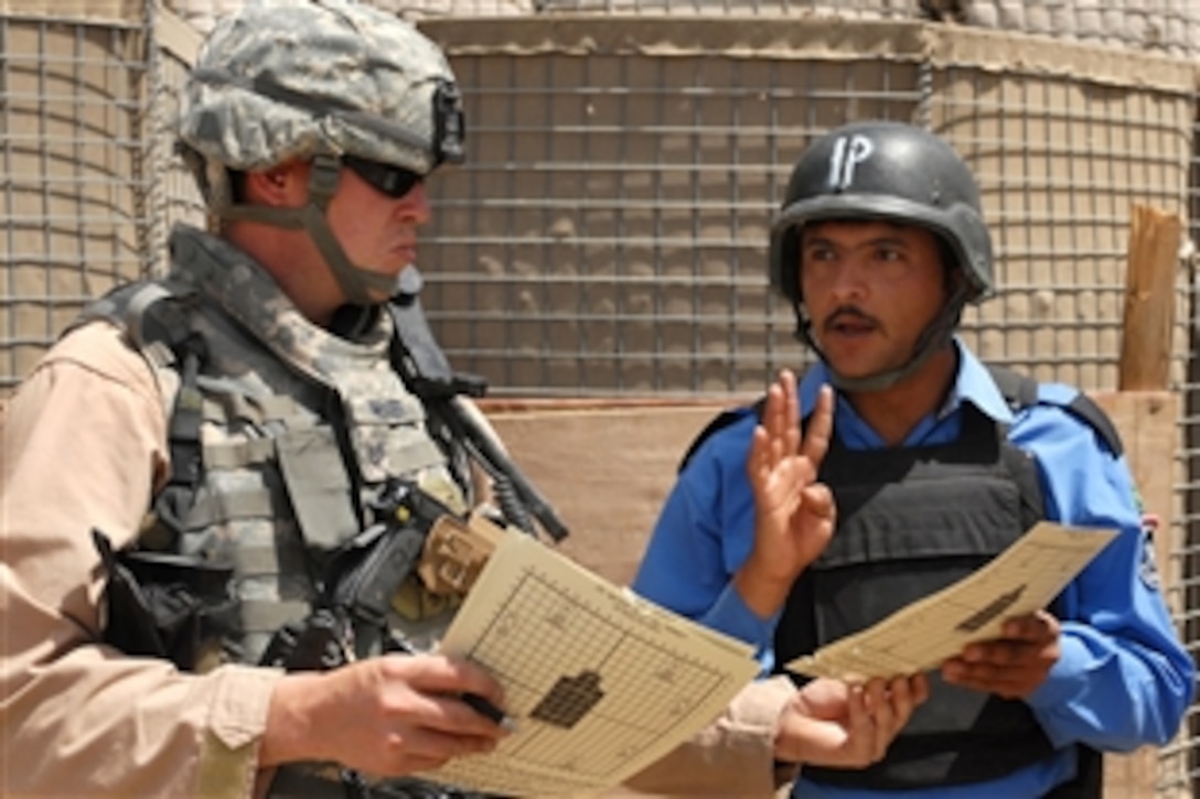U.S. Air Force Tech. Sgt. Shadd McKee scores a target shot by an Iraqi policeman at a firing range in Mahmudiyah, Iraq, April 23, 2009. U.S. troops are teaching Iraqi policemen how to safely aim and fire their weapons. These policemen will then be sent out to instruct other Iraqi police officers throughout Iraq. McKee is assigned to the Rough Riders, 91st Battalion.