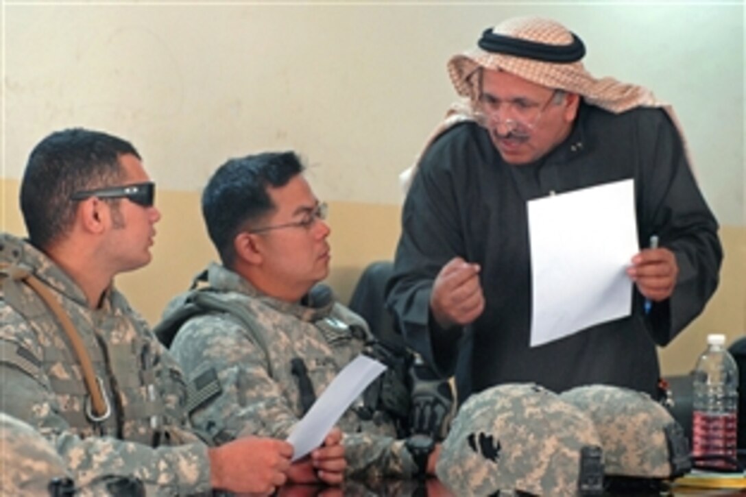 U.S. Army Sgt. Federico Ampil, center, speaks with a neighborhood leader at a key leader meeting in Khan Dhari, Iraq, April 20, 2009. Ampil and fellow is assigned to the 1st Infantry Division's 2nd Brigade.