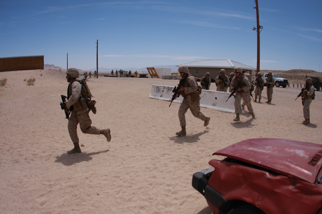 Marines with Company C, 1st Tank Battalion, dash into an urban assault course past the wreckage of a vehicle April 28 at the Combat Center’s Range 111. The company conducted the operation as part of their pre-deployment training process.