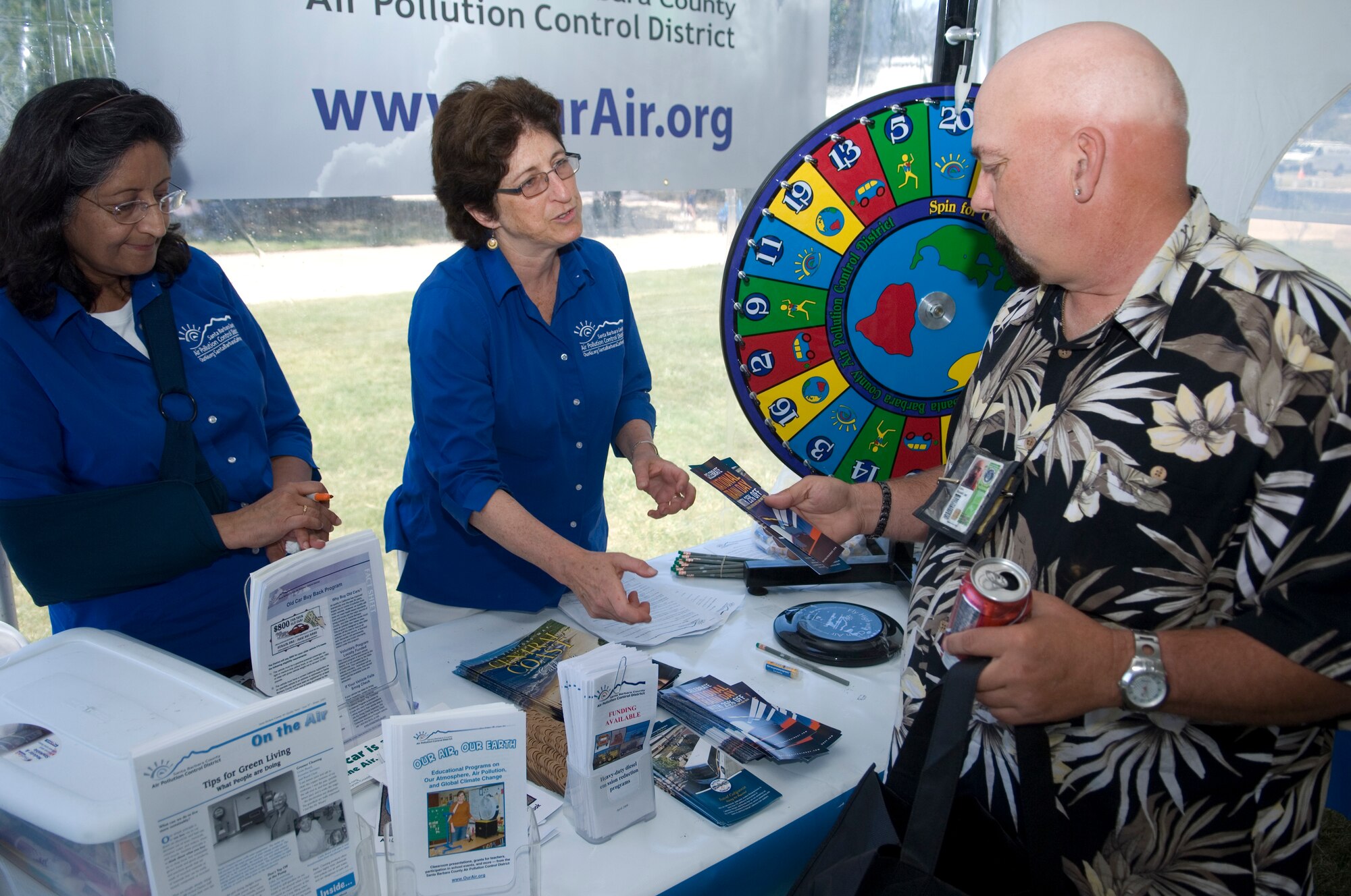 VANDENBERG AIR FORCE BASE, Calif. -- Ron Case, a contractor from the 30th Civil Engineer Squadron, receives brochures from Mary Byrd and Vijaya Jammalamdaka, both from the Santa Barbara County Air Pollution Control District, during the Earth Day Fair on April 22 here. The Earth Day Fair had multiple stands containing various information on how to make the world a healthier environment. (U.S. Air Force photo/Airman 1st Class Andrew Lee)