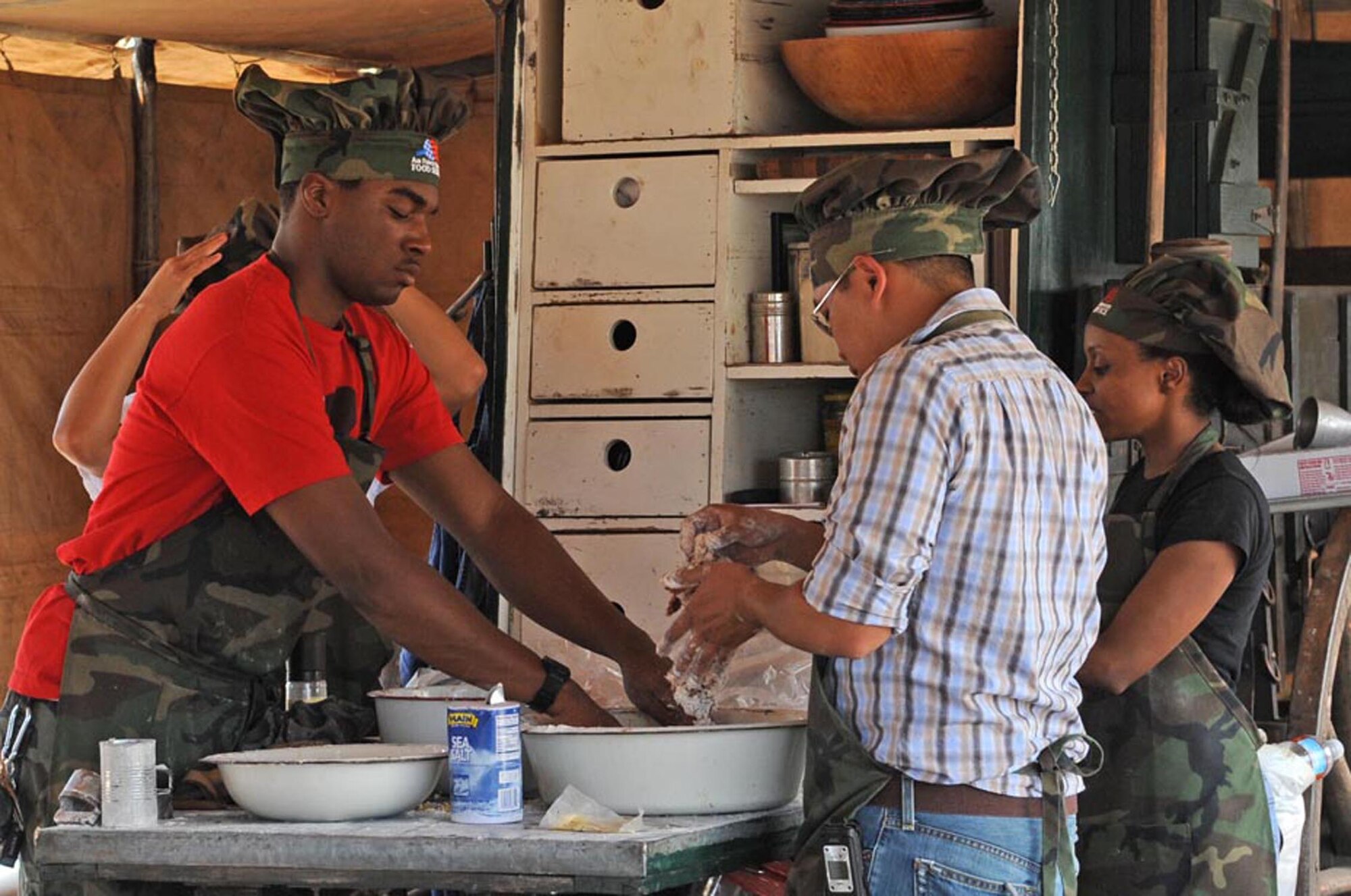 CANNON AIR FORCE BASE, N.M. -- (Left) Airman Dominique Smith, 27th Special Operations Force Support Squadron, (right) Staff Sgt. Rhallete Javier, 27th Special Operations Civil Engineer Squadron, and Senior Airman Yemisirach Alemayehu, 27th Special Operations Force Support Squadron, bread steaks for frying during the 2nd Annual 'Duke of the Dutch Ovens ' Chuck Wagon Cook-Off April 25. The Chuck Wagon Cook-Off is held every year at the Curry County Fairgrounds and proceeds go to the Miss Rodeo New Mexico Pageant and Scholarships fund.  (U.S. Air Force Photo/Staff Sgt. Heather Redman)