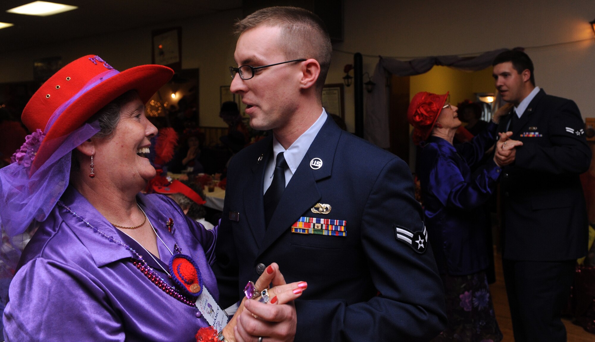 MOUNTAIN HOME AIR FORCE BASE, Idaho -- Airman 1st Class Brandon Ashby, 366th Logistics Readiness Squadron vehicle operator, dances with Nancy Winkowski, a queen in the Red Hat Society, at the American Legion in Mountain Home April 25. Eight drivers from the 366th LRS volunteered to drive more than 157 Red Hat Society members around Elmore County during their annual “funvention” event, which was held in Mountain Home over the weekend. The Red Hat Society is a network of women approaching age 50 and beyond. (U.S. Air Force photo/Airman 1st Class Debbie Lockhart)