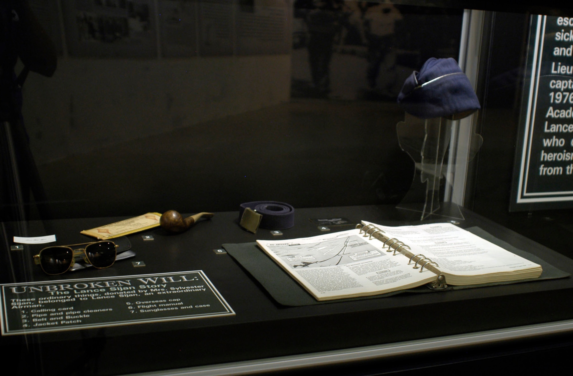 DAYTON, Ohio - Calling card, pipe and pipe cleaners, belt and buckle, jacket patch, overseas cap, flight manual, sunglasses and case that belonged to Lance Sijan, donated by Mrs. Sylvester Sijan. (U.S. Air Force photo)q