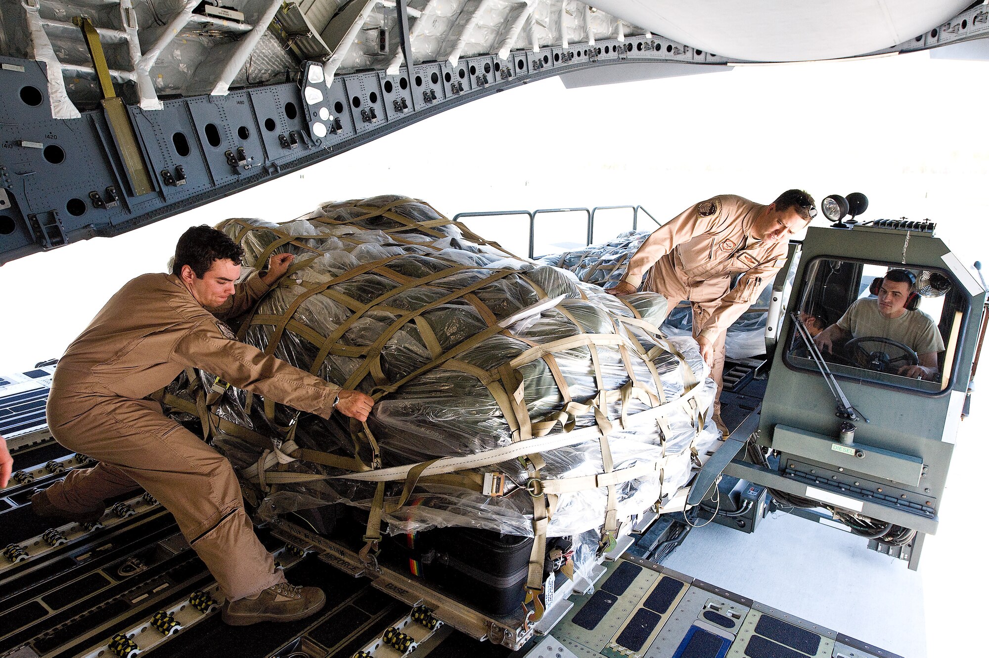 (From left) Airman 1st Class Timothy Davis and Master Sgt. William Flanders, 3rd Airlift Squadron loadmasters, load cargo into a C-17 Globemaster III for the 3rd AS squadron deployment April 26.  (U.S. Air Force photo\Roland Balik)