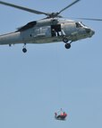 AW1 James Davis, SH-60F crewchief, NAS Key West, Fla., raises a student in the basket during the helicopter hoist phase of water survival training at NAS Key West, Fla.  Water survival training is required every two years for all air crew and aero medical personnel. (Air Force photo/Master Sgt. Kerry Bartlett)